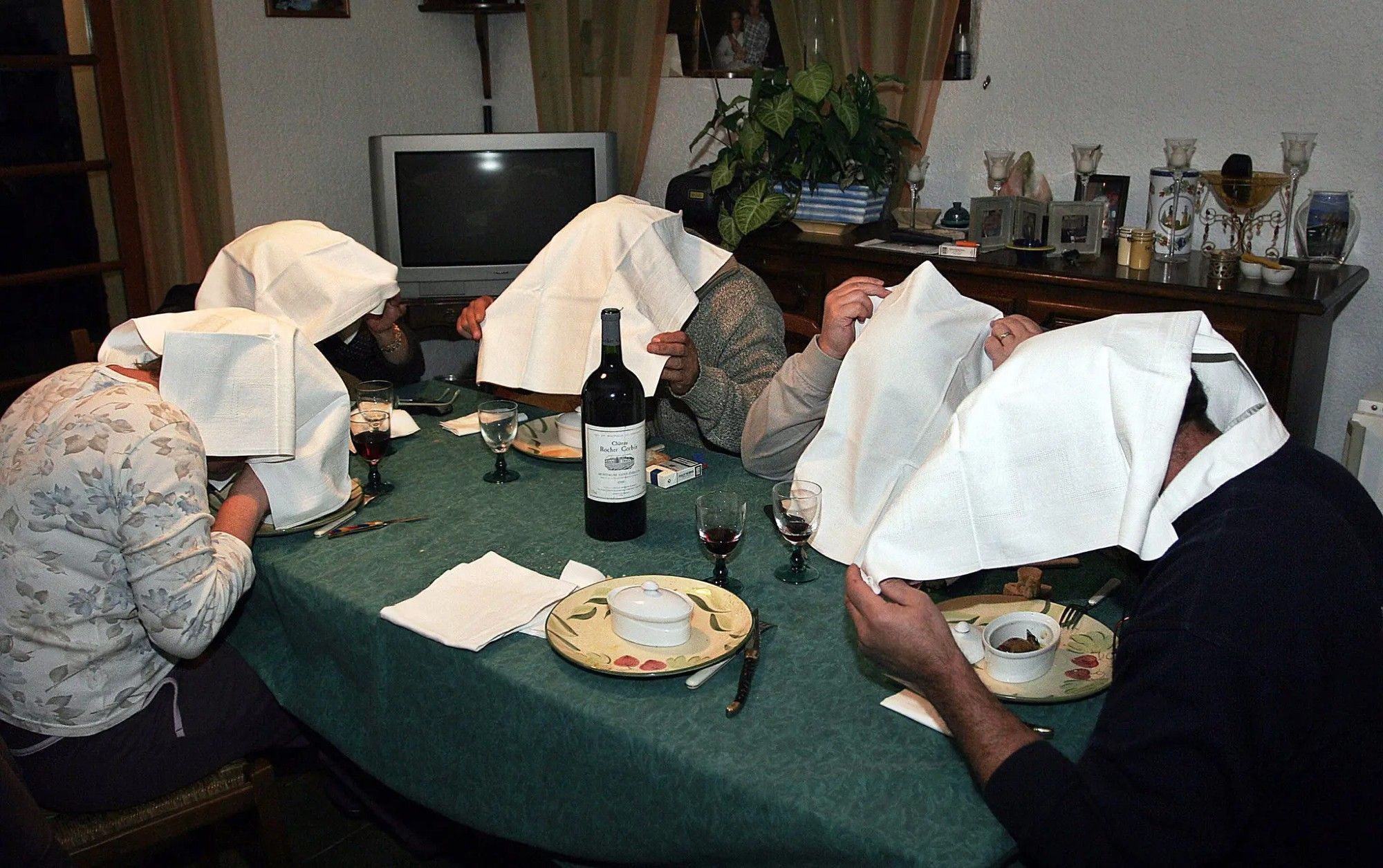 a group of people eating ortolan with napkins over their heads