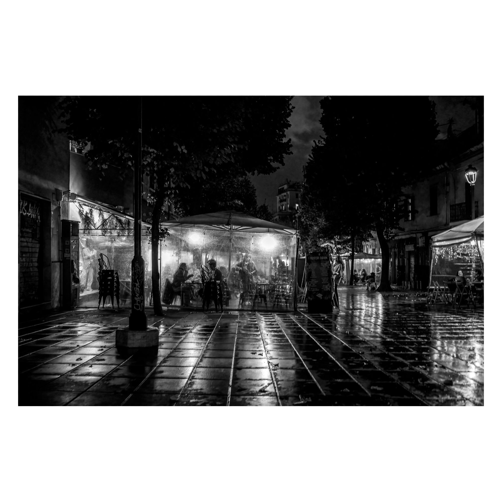 nightshot of people in transparent tents , rain and reflective ground