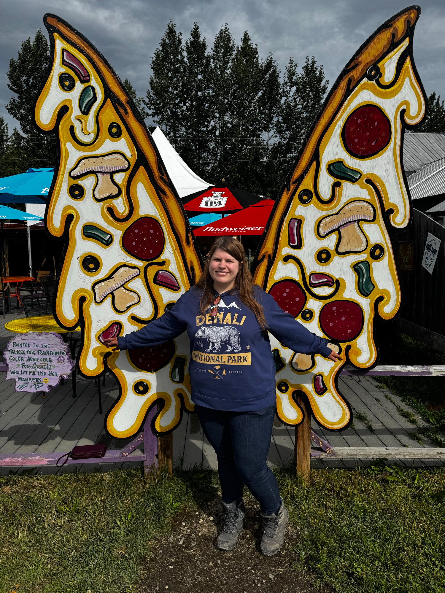 A woman standing in front of fairy wings shaped like pizza.