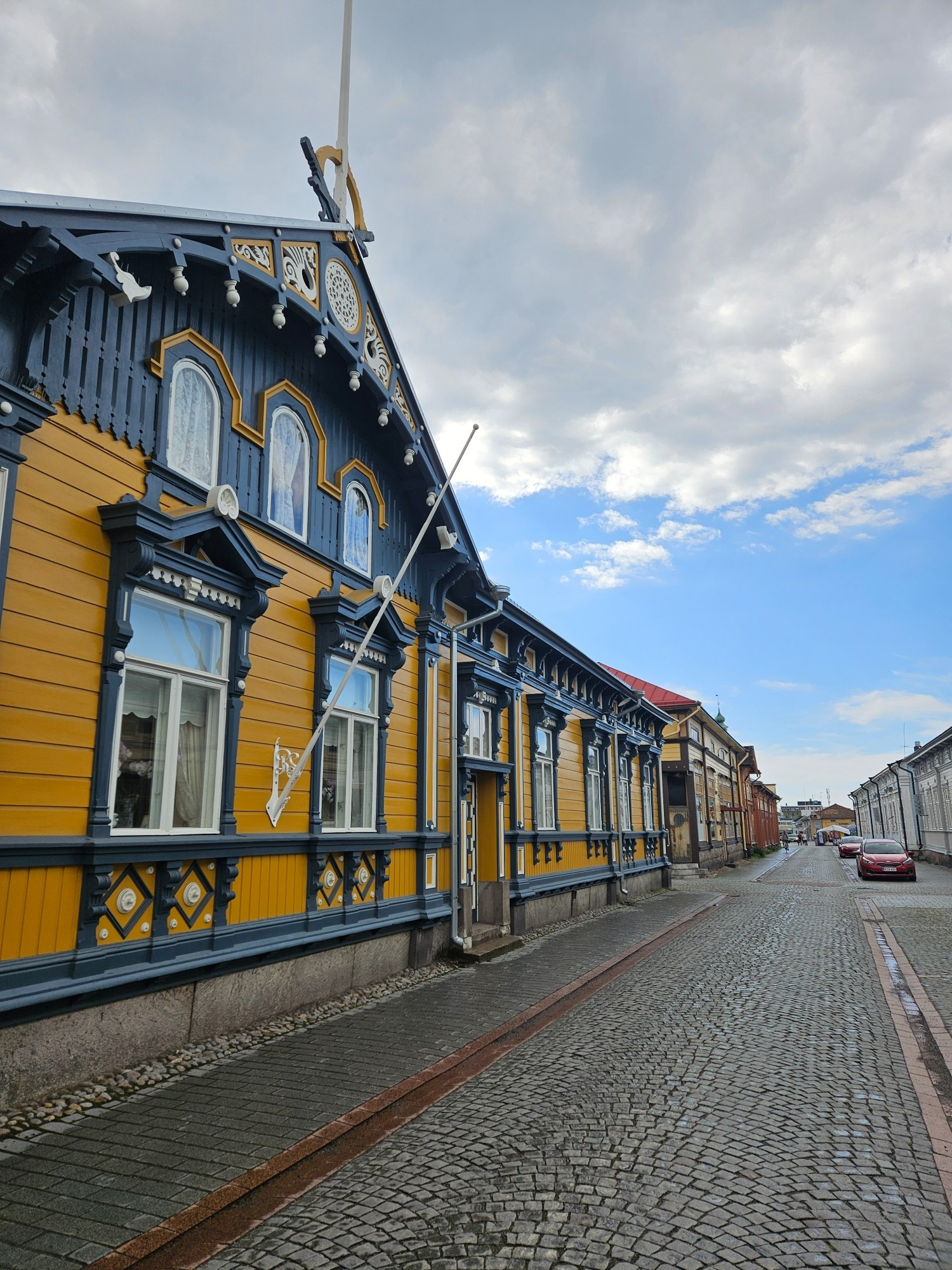 Old cobbled street with a facade of a fancy wooden building on the left