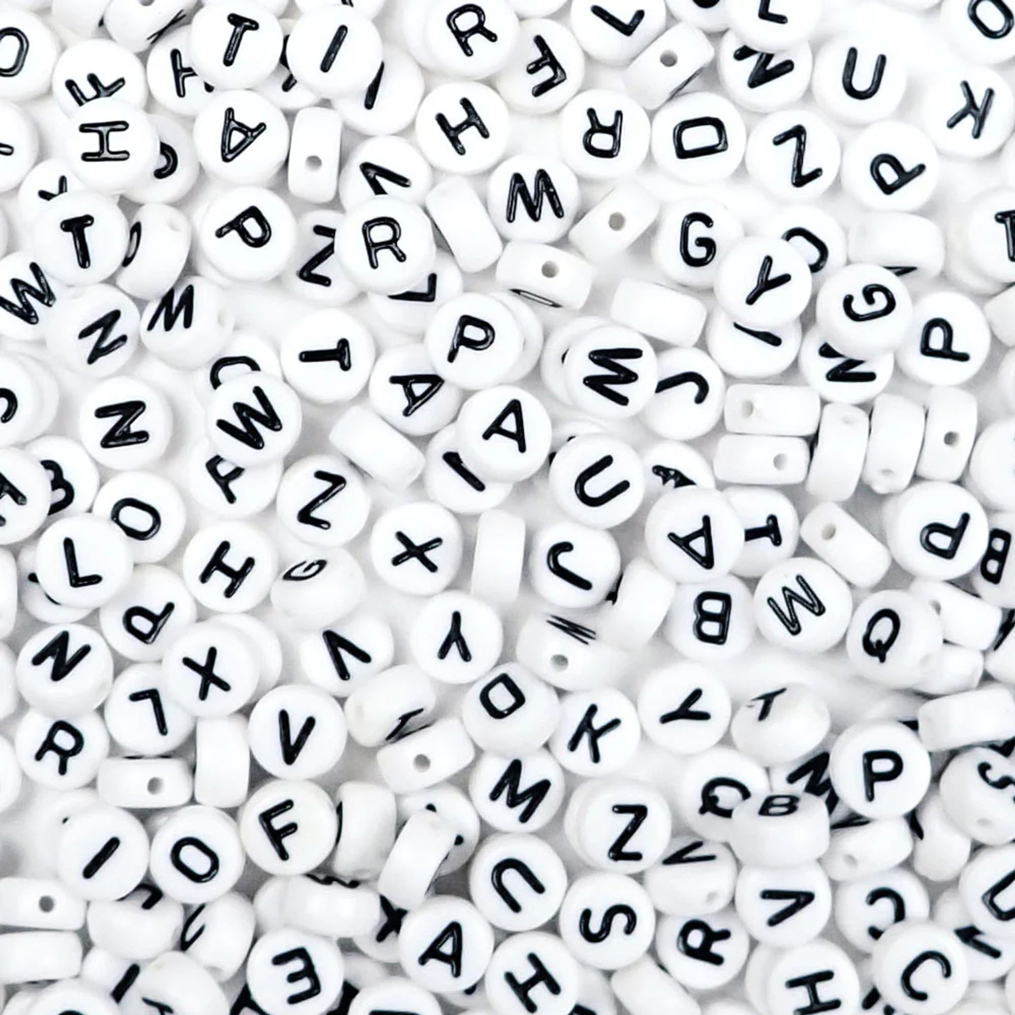 image of a pile of white, circular beads with black english alphabet letters on them