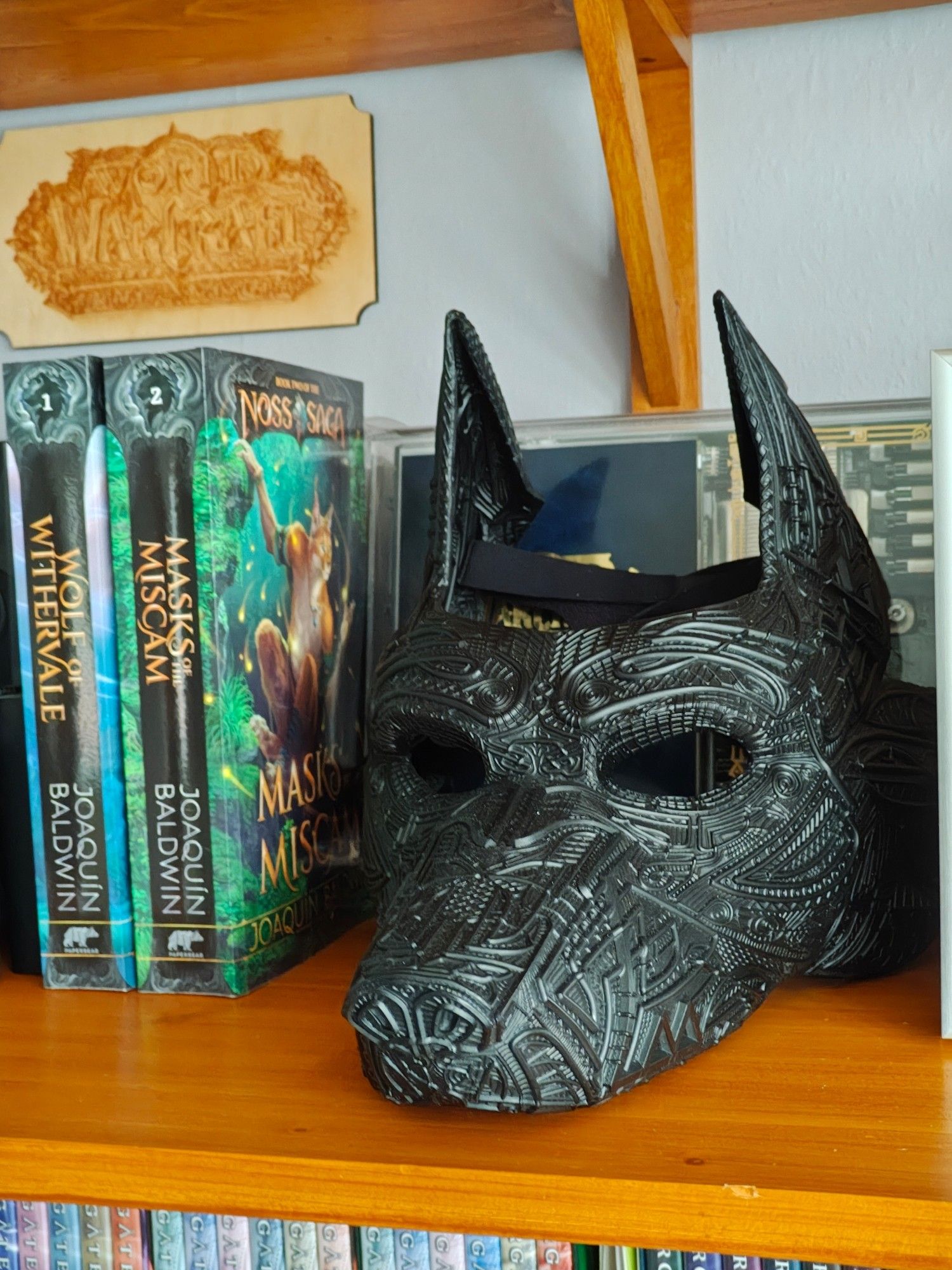 Agnargsilv the canid mask on a shelf next to books 1 and 2 of the Noss Saga