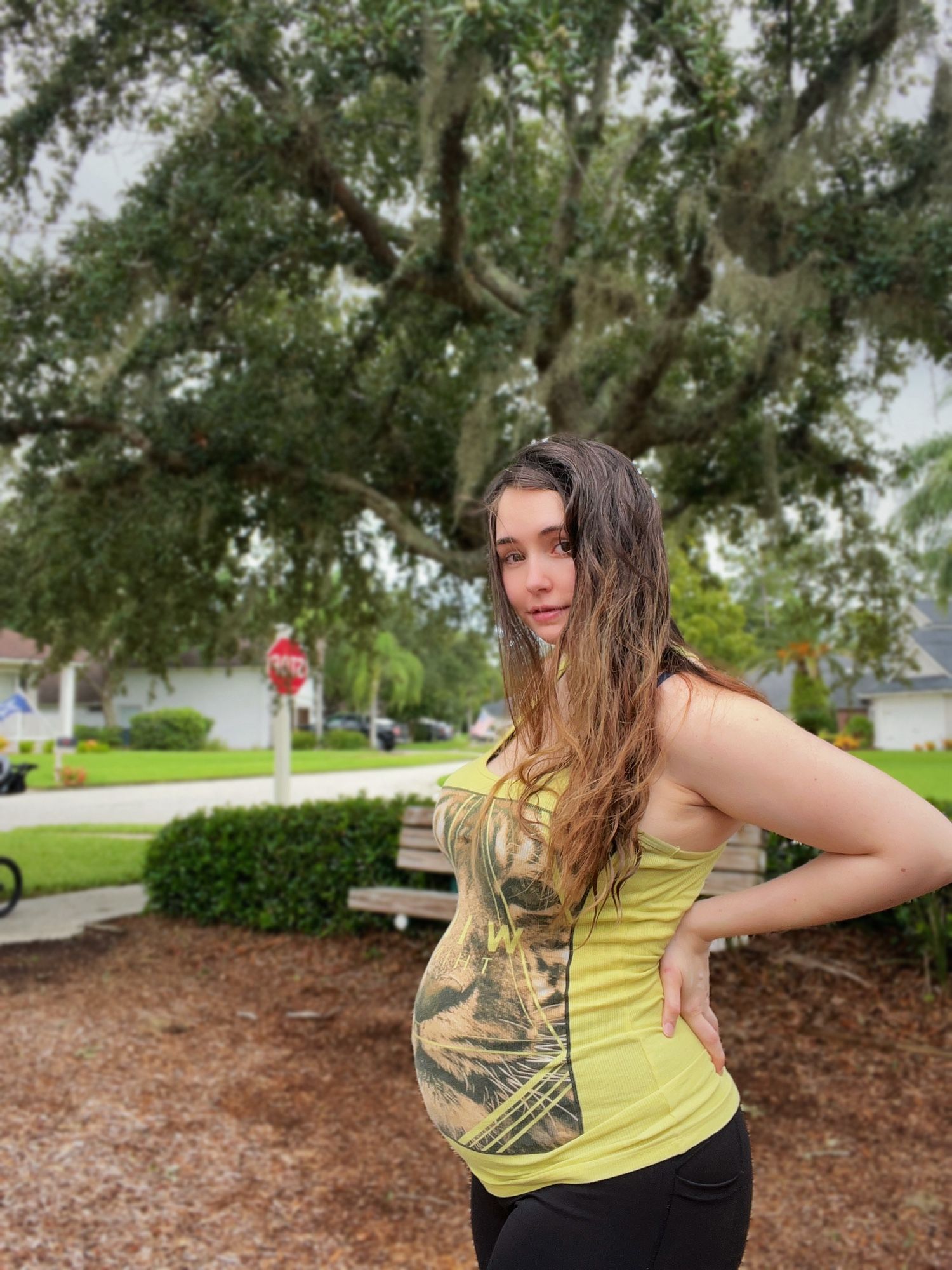 Picture of me at the park showing off my pregnant belly wearing a yellow tank top with a tiger on it