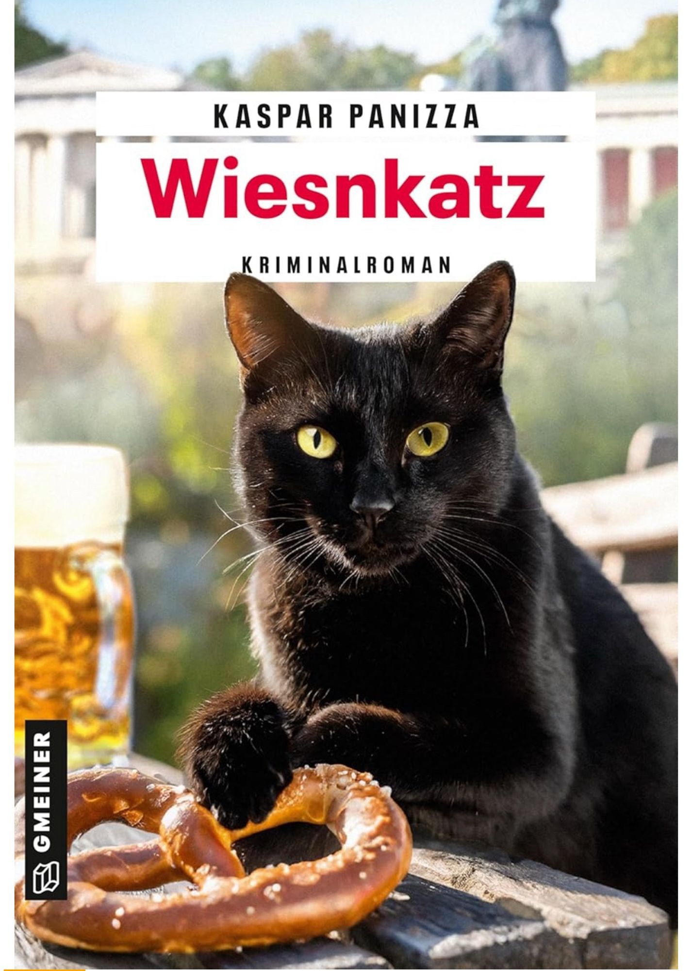 Auf dem Bild ist ein Buchcover zu sehen. Im Vordergrund befindet sich eine schwarze Katze mit gelben Augen, die neben einer Brezel und einem Bierkrug sitzt. Der Titel des Buches lautet „Wiesnkatz“, geschrieben von Kaspar Panizza. Im Hintergrund erkennt man eine unscharfe Außenumgebung, die an ein traditionelles bayrisches Biergarten-Setting erinnert. Es handelt sich um einen Kriminalroman, veröffentlicht vom Gmeiner Verlag.