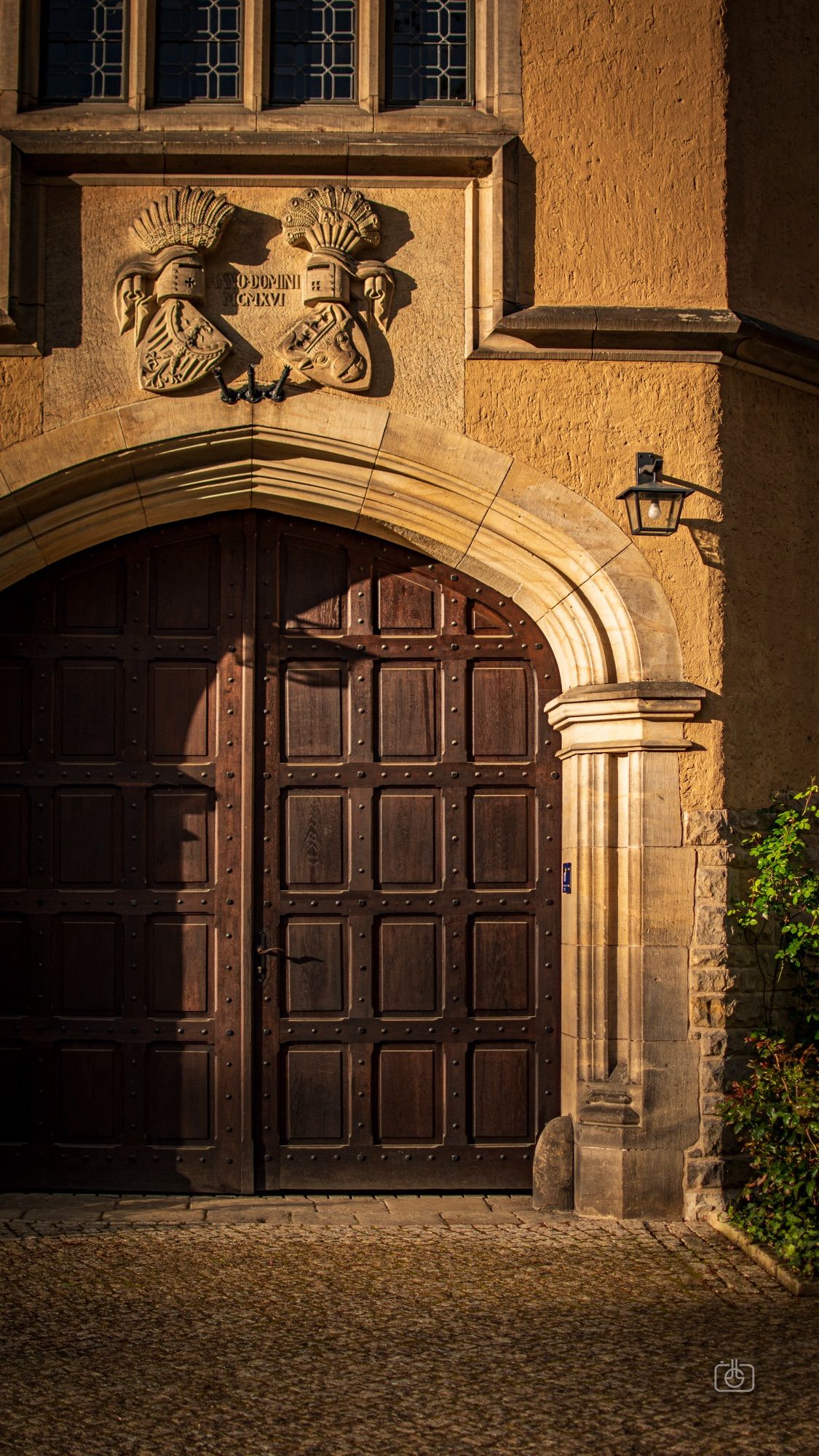 Closed heavy wooden door in gatehouse of a mock Tudor manor at sunset. Cecilienhof Palace, Potsdam, 22 Apr 2024. Nikon D5600, Nikkor DX 35 mm ƒ1.8G, ISO 100, ƒ2.5, -0.3 ev, 1/1250s