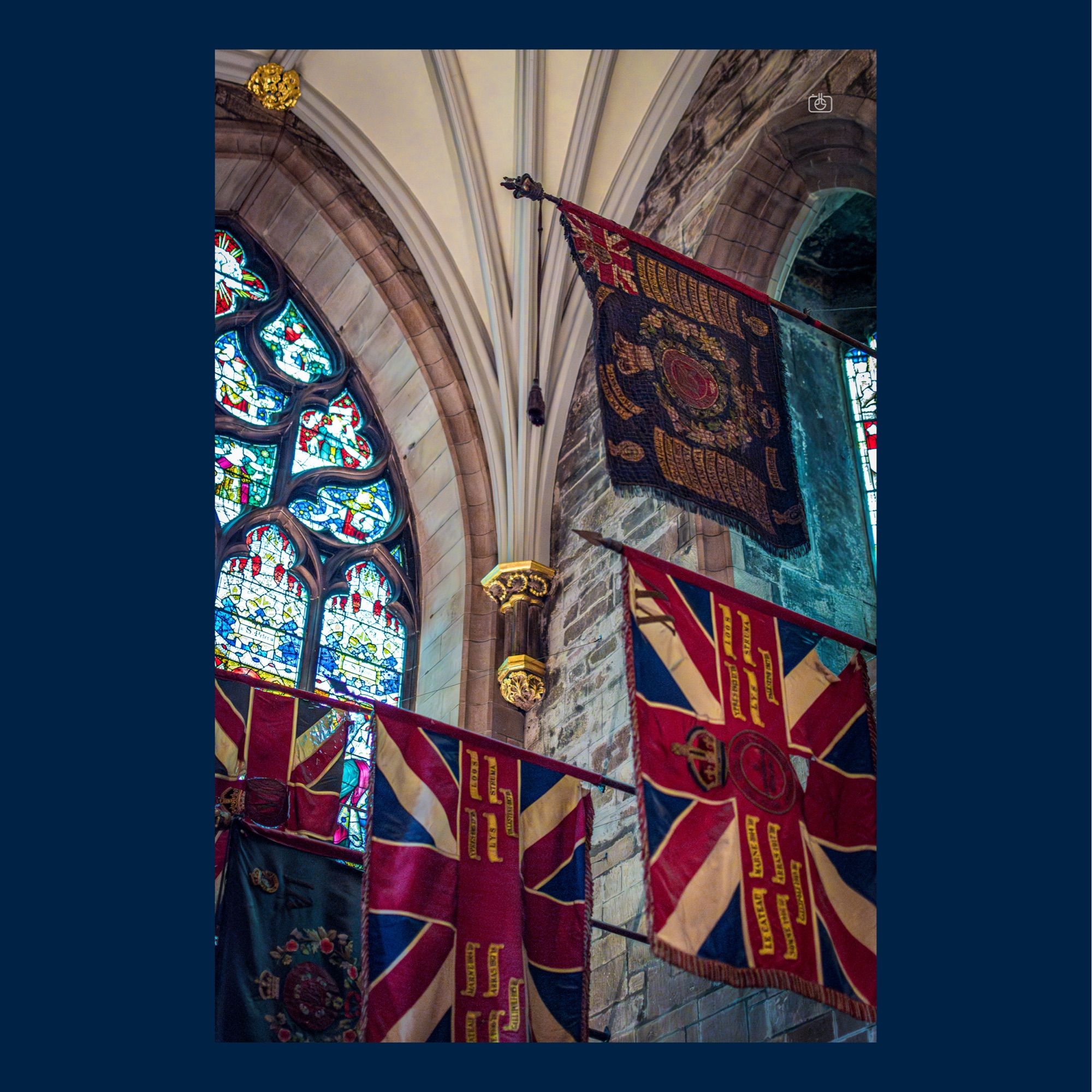 Regimental flags fly in a side aisle of a Gothic cathedral under gilded finials and arches. St. Giles’ Cathedral, Edinburgh, 19 Aug 2024. Nikon D5600, Nikkor DX 35 mm ƒ1.8G, ISO 5000, ƒ2.2, -0.3 ev, 1/160s