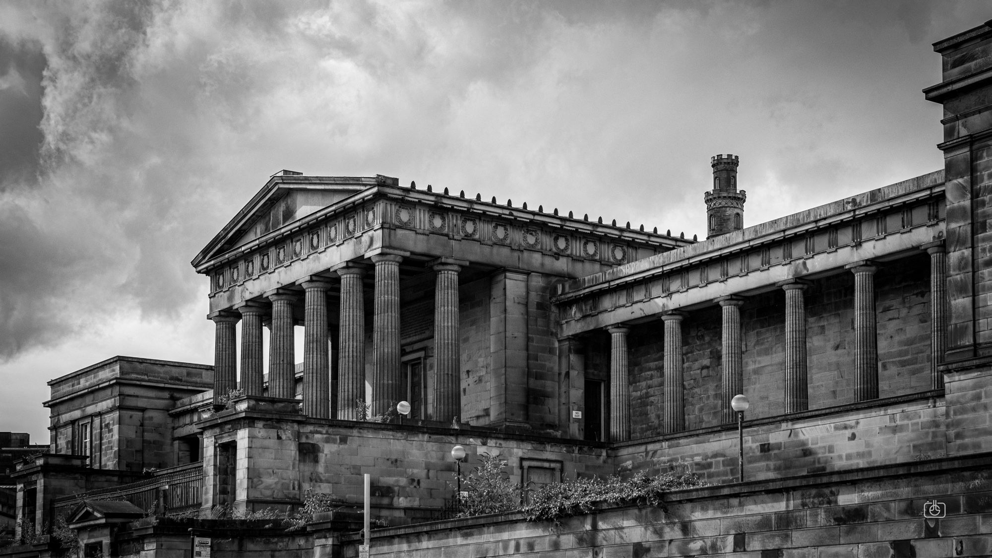 The crumbling façade of the palatial Old Royal High School under a brooding sky. Once mooted as a location for the devolved Scottish Parliament, it has remained unused for many years. Old Royal High School, Regent Road, Edinburgh, 23 Aug 2024. Nikon D5600, Nikkor DX 35 mm ƒ1.8G, ISO 400, ƒ3.2, -0.3 ev, 1/800s