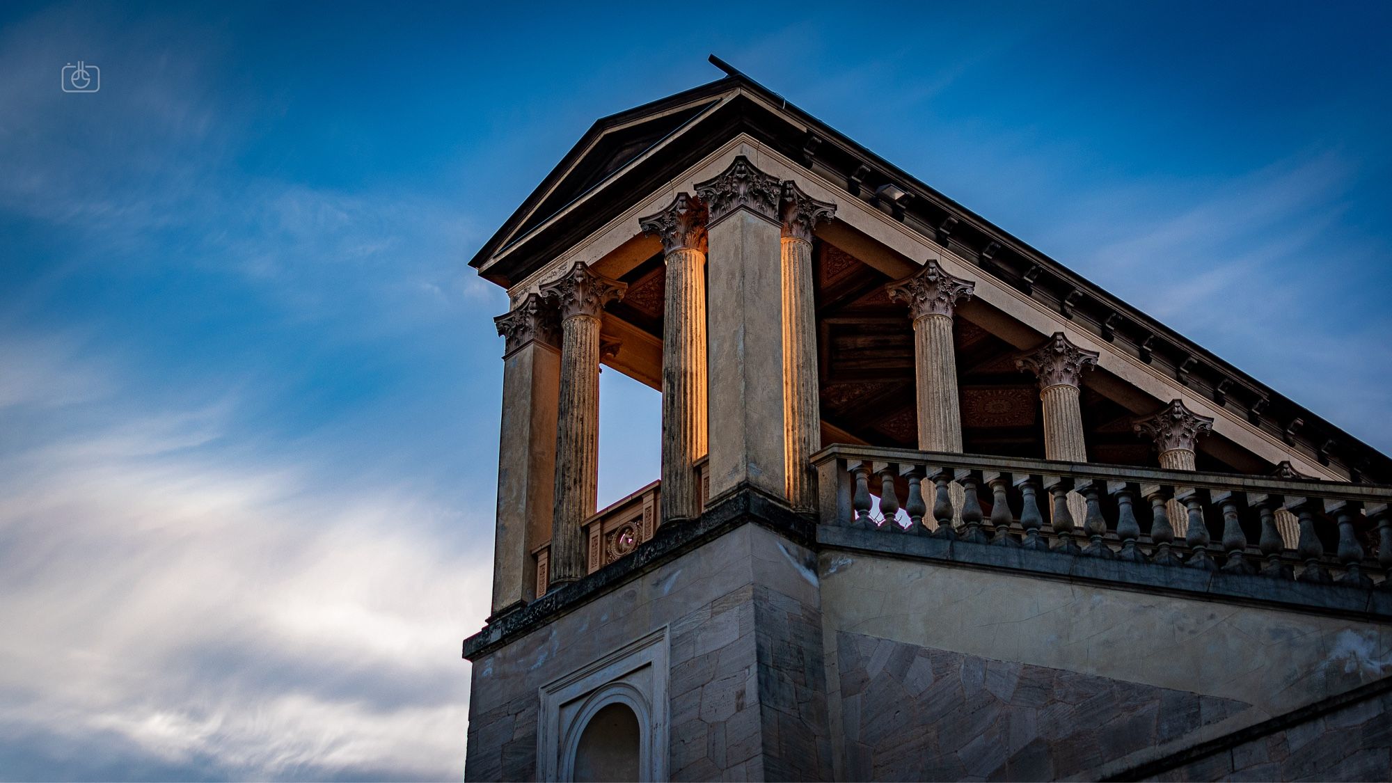 The setting sun hitting neoclassical columns of a temple-like structure from behind, causing them to glow. Belvedere on the Pfingstberg, Potsdam, 18 Mar 2024. Nikon D5600, Nikkor DX 35 mm ƒ1.8G, ISO 100, ƒ2.2, -0.3 ev, 1/2500s