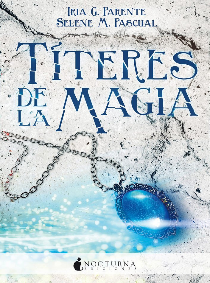 Portada del libro Títeres de Magia de Iria G. Parente y Selene M. Pascual. En ella vemos un colgante con una joya azul marino que brilla y el fondo es como una pared de roca quebrada.