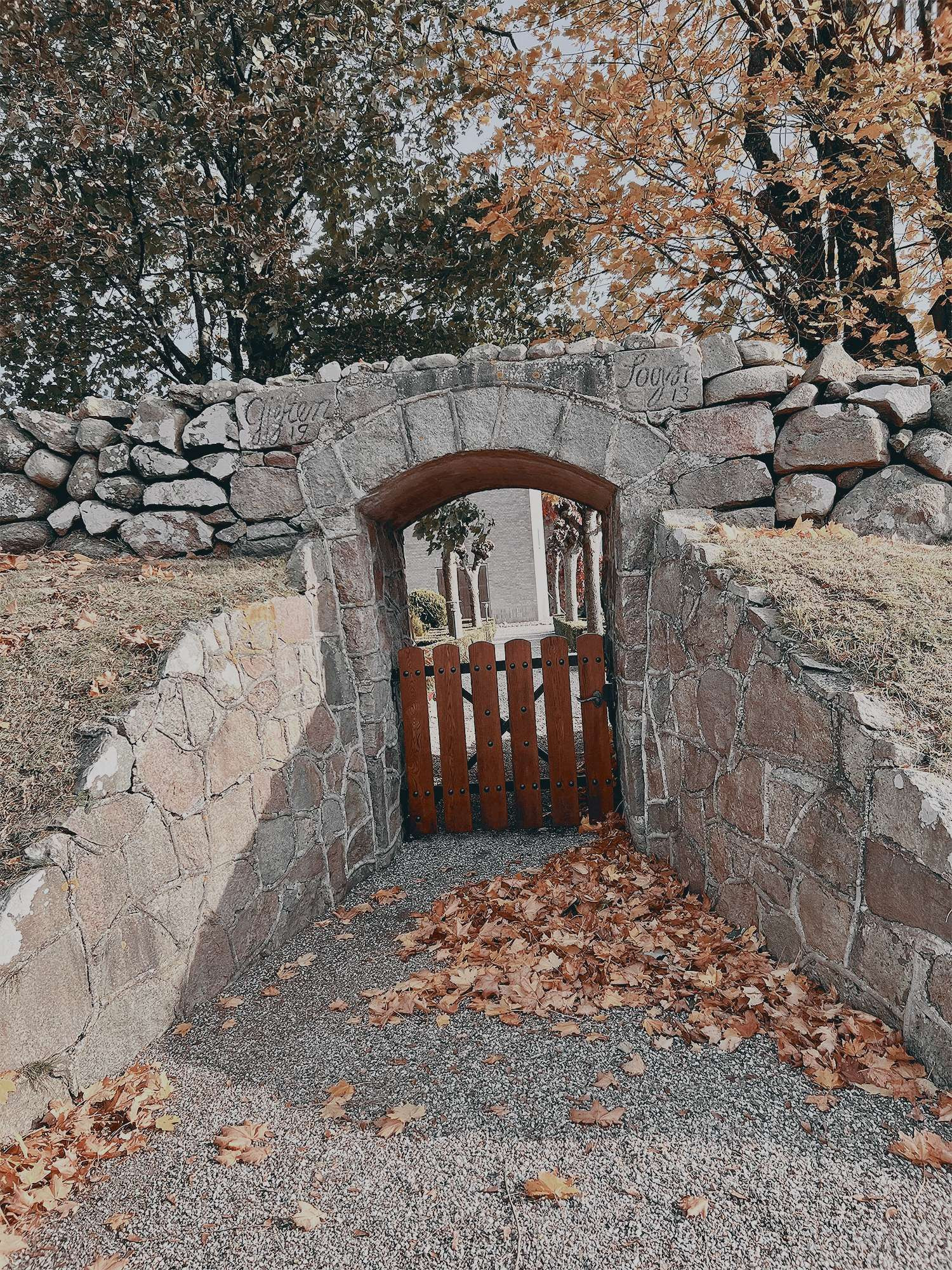 A really cute stone archway that has nice crunchy autumn leafs on the floor.