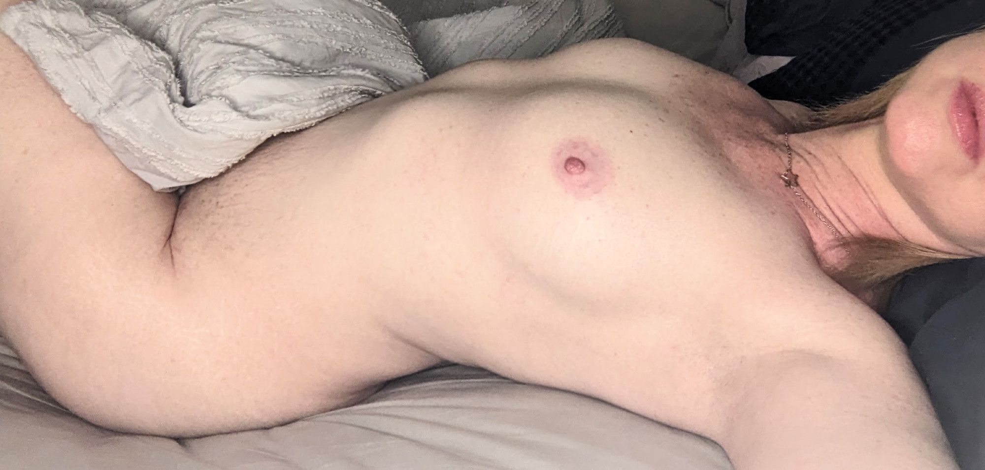 Nude, laying in bed, showing boobs