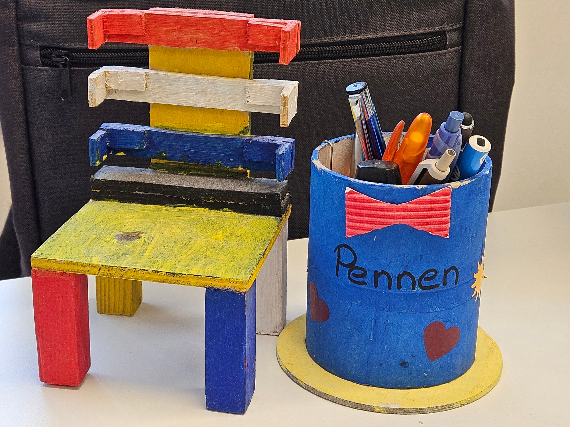 Een houten stoeltje in primaire kleuren en een pennenbak