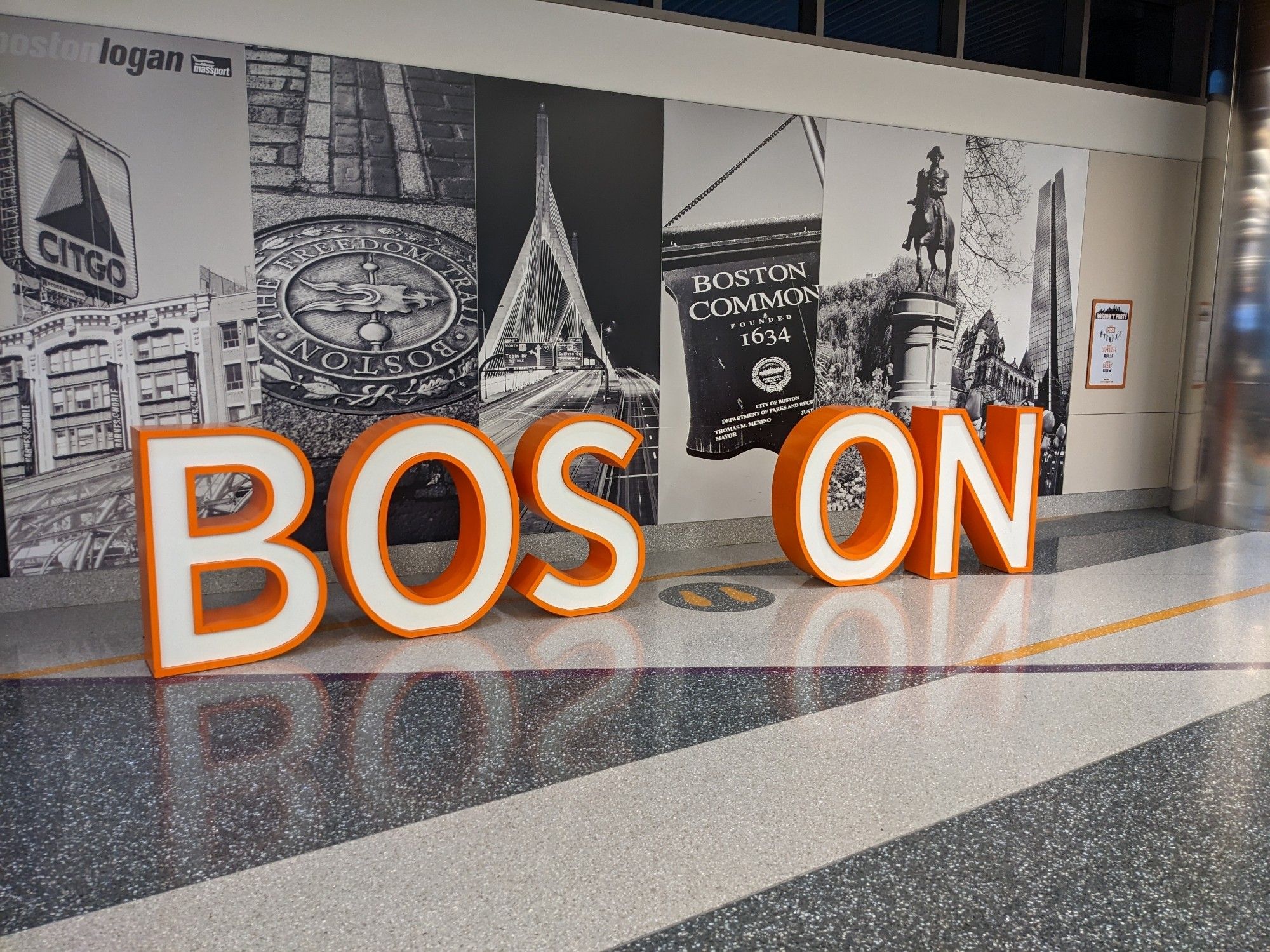 Big sign in airport lounge made of 3-foot tall letters that spell "Boston." Except the T is missing, making the sign spell "boson."