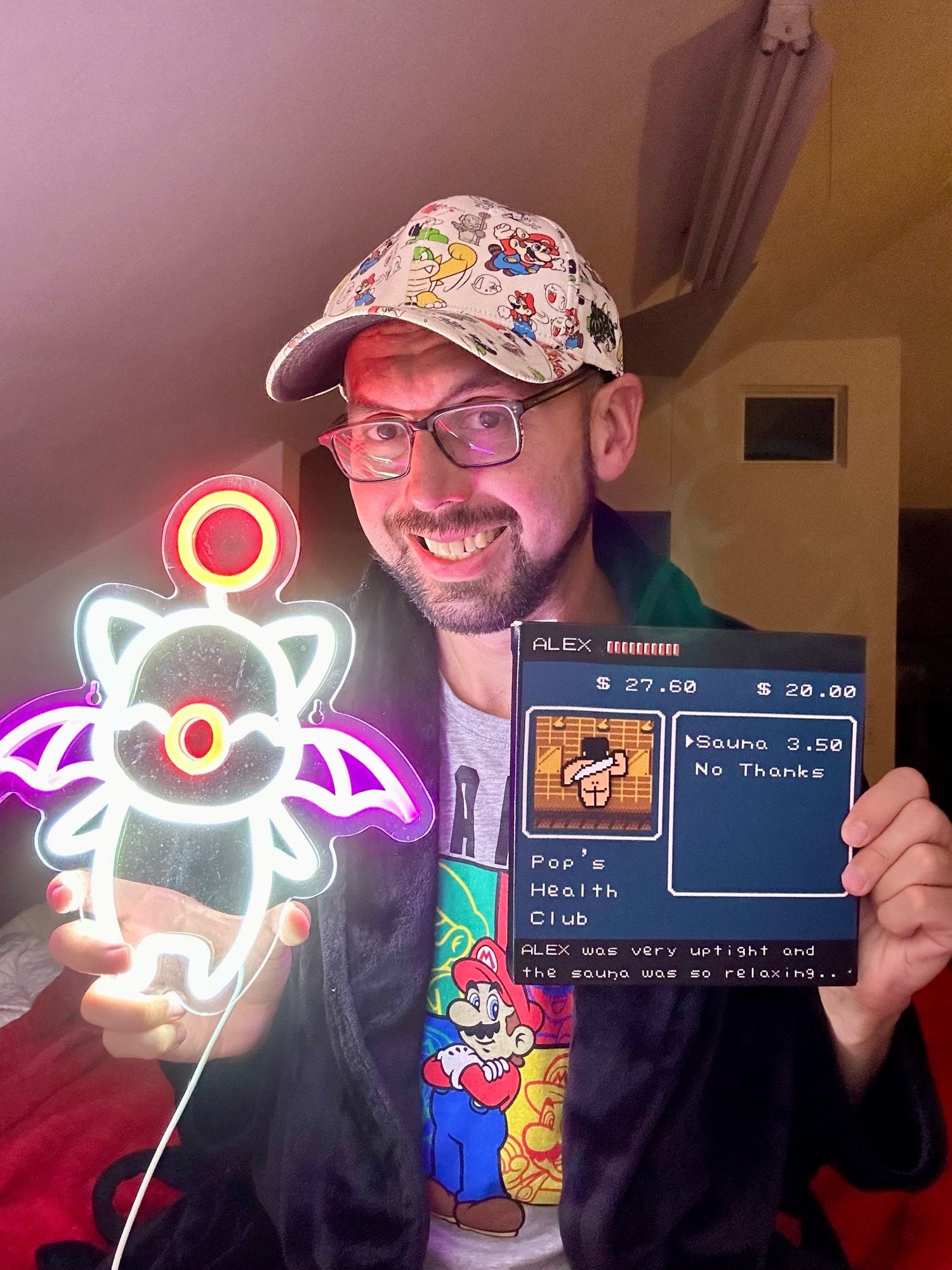 Me wearing a sweet retro Mario 3 hat and holding a dazzlingly lit neon moogle and a depiction of the iconic sauna scene from River City Ransom