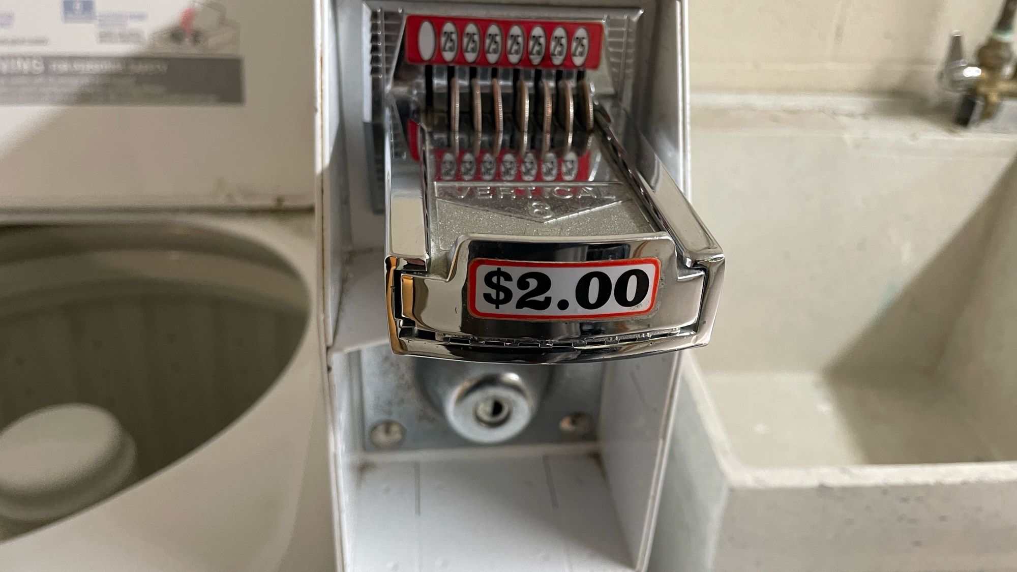 A laundry machine coin slot that says it costs $2 to do a load of wash.