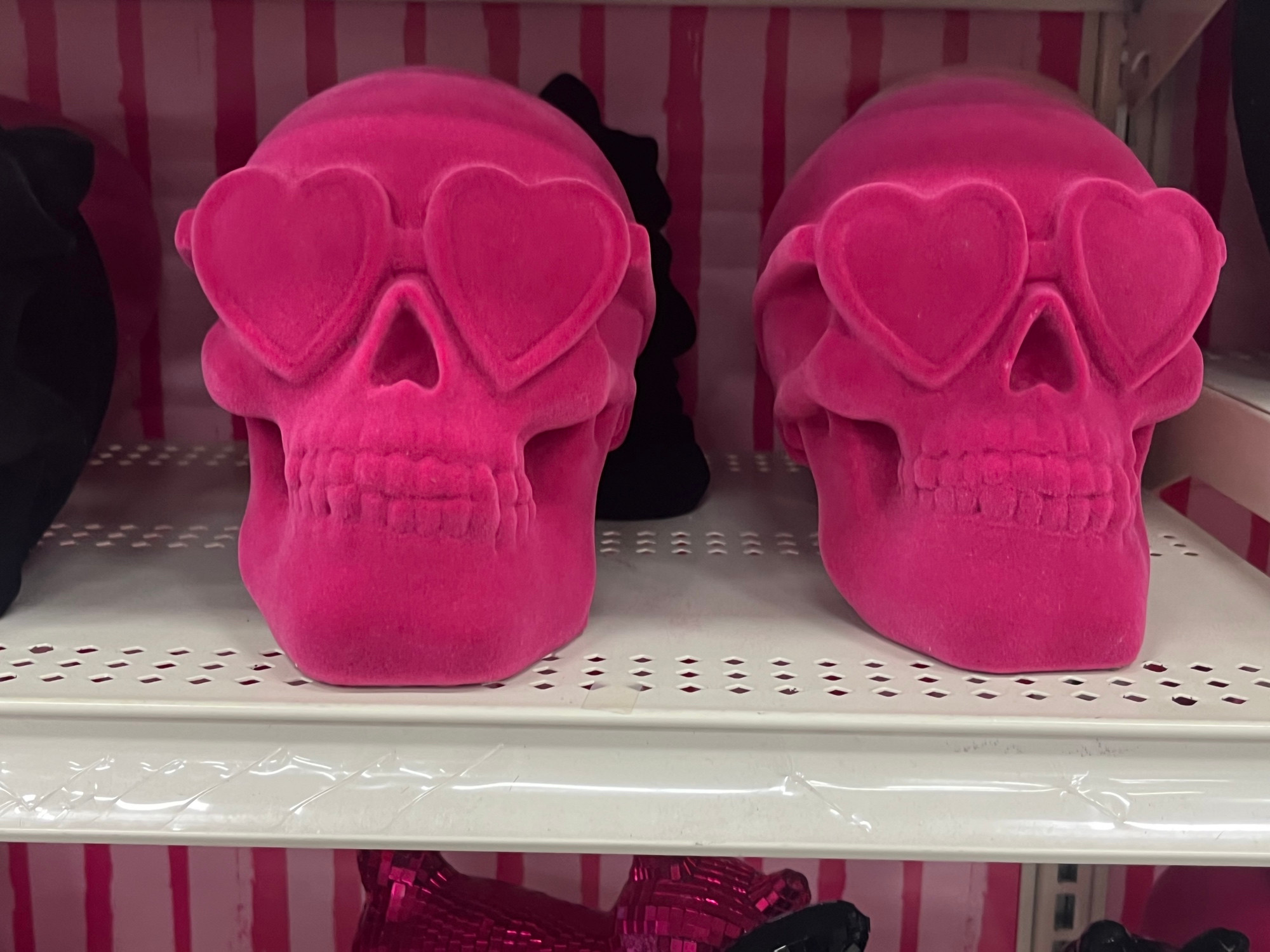 Two pink flocked skulls wearing heart shaped glasses