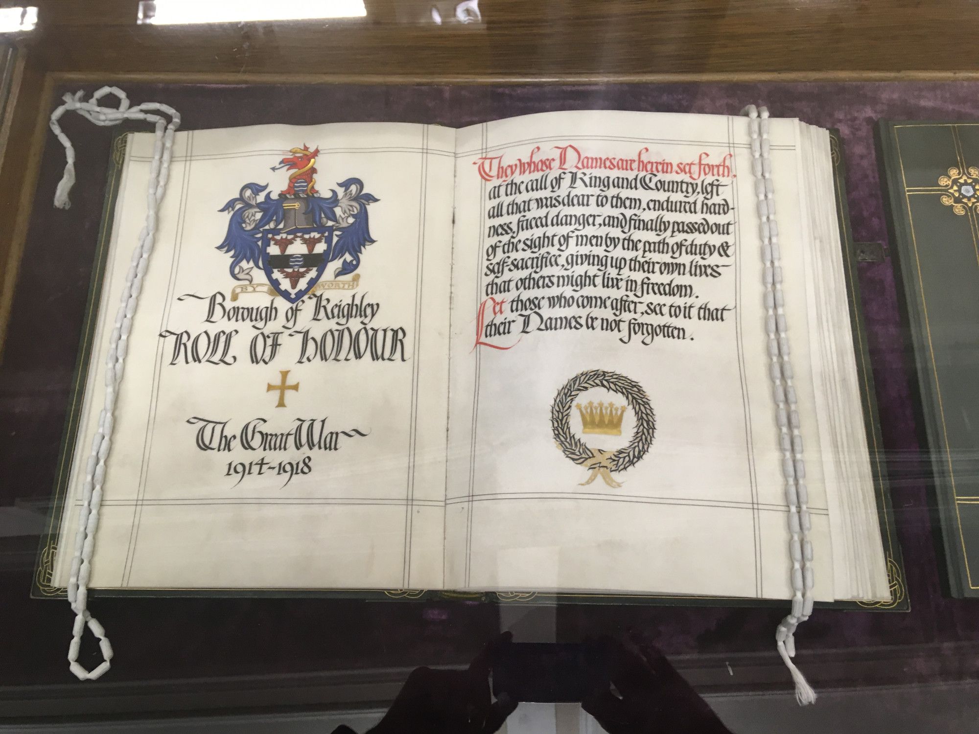 A leather and vellum roll of honour with beautifully illuminated imagery and text, giving details of the Keighley Coat of Arms and the words in ornamental script describing the contents of the book.