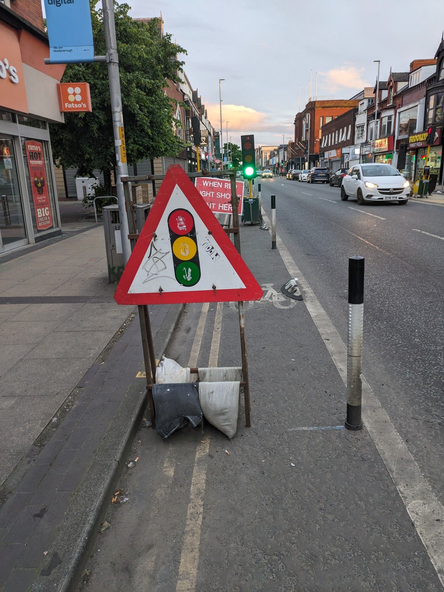 Traffic light sign and stop here sign in bike lane ahead of temporary stop light (also in bike lane)