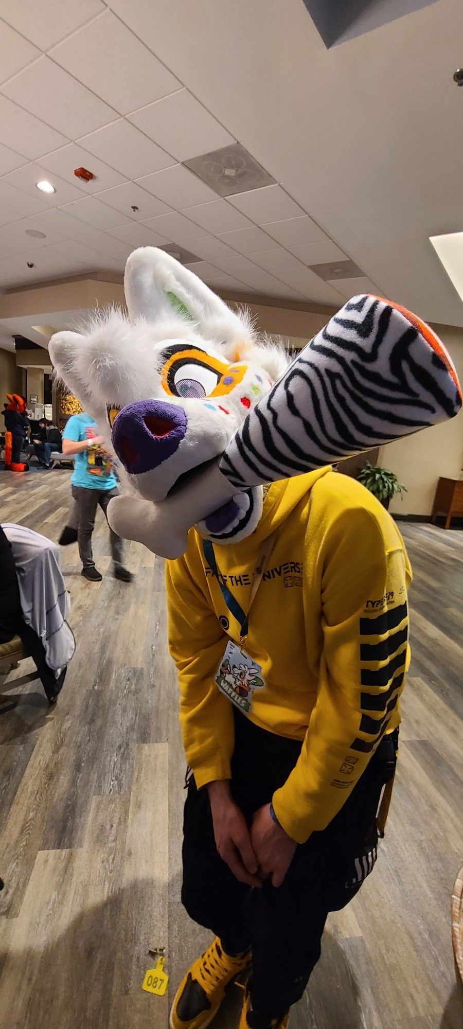 Fursuiter with zebra colored meat plushy in their mouth.