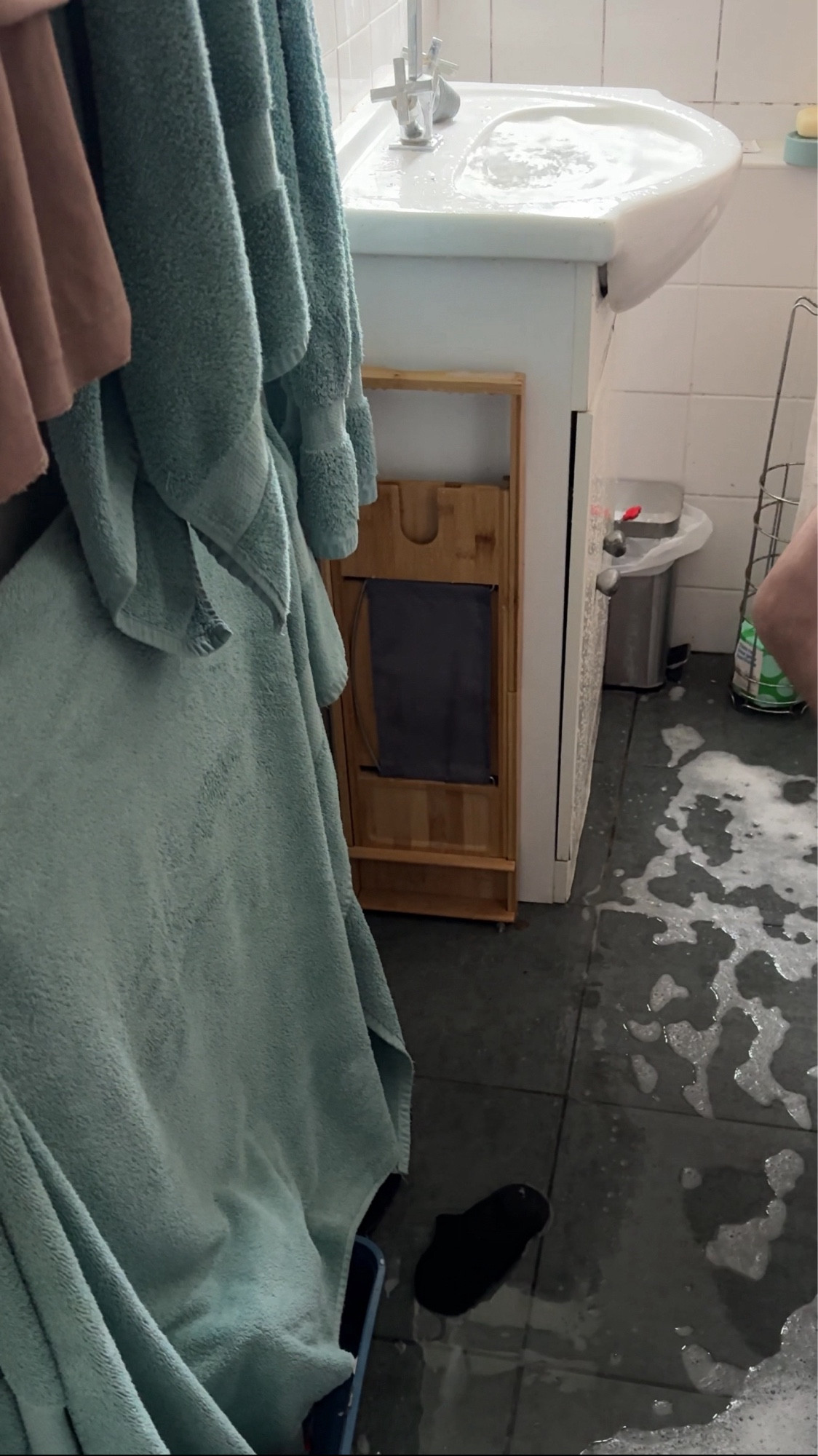 A picture of a bathroom sink, overflowing with water coming up from the drain. The floor is covered in wastewater.