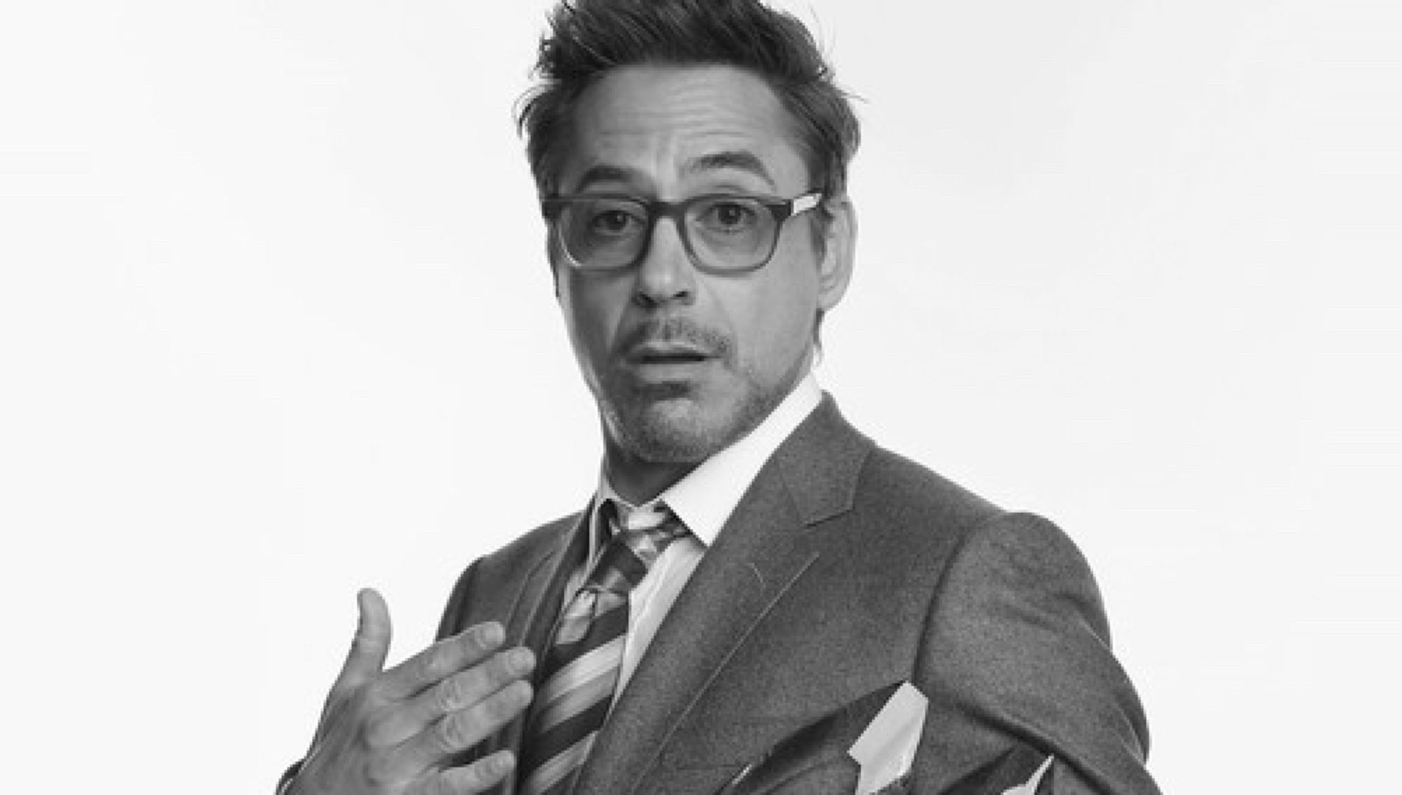 A black and white picture of Robert Downey Jr. with a white background in a pose where he seems to be explaining something.