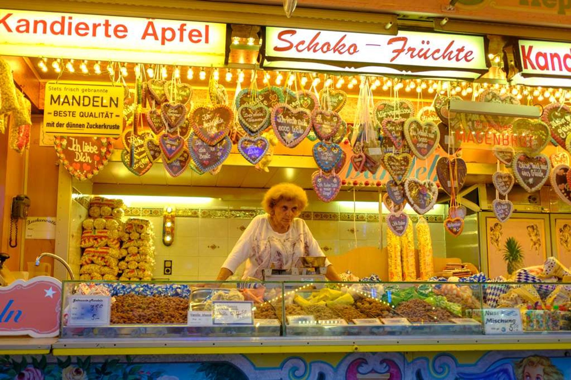 Eine Süßwarenverkäuferin auf einer Kirmes/Volksfest schaut grimmig aus ihrem bunten Süßwarenladenwagen heraus