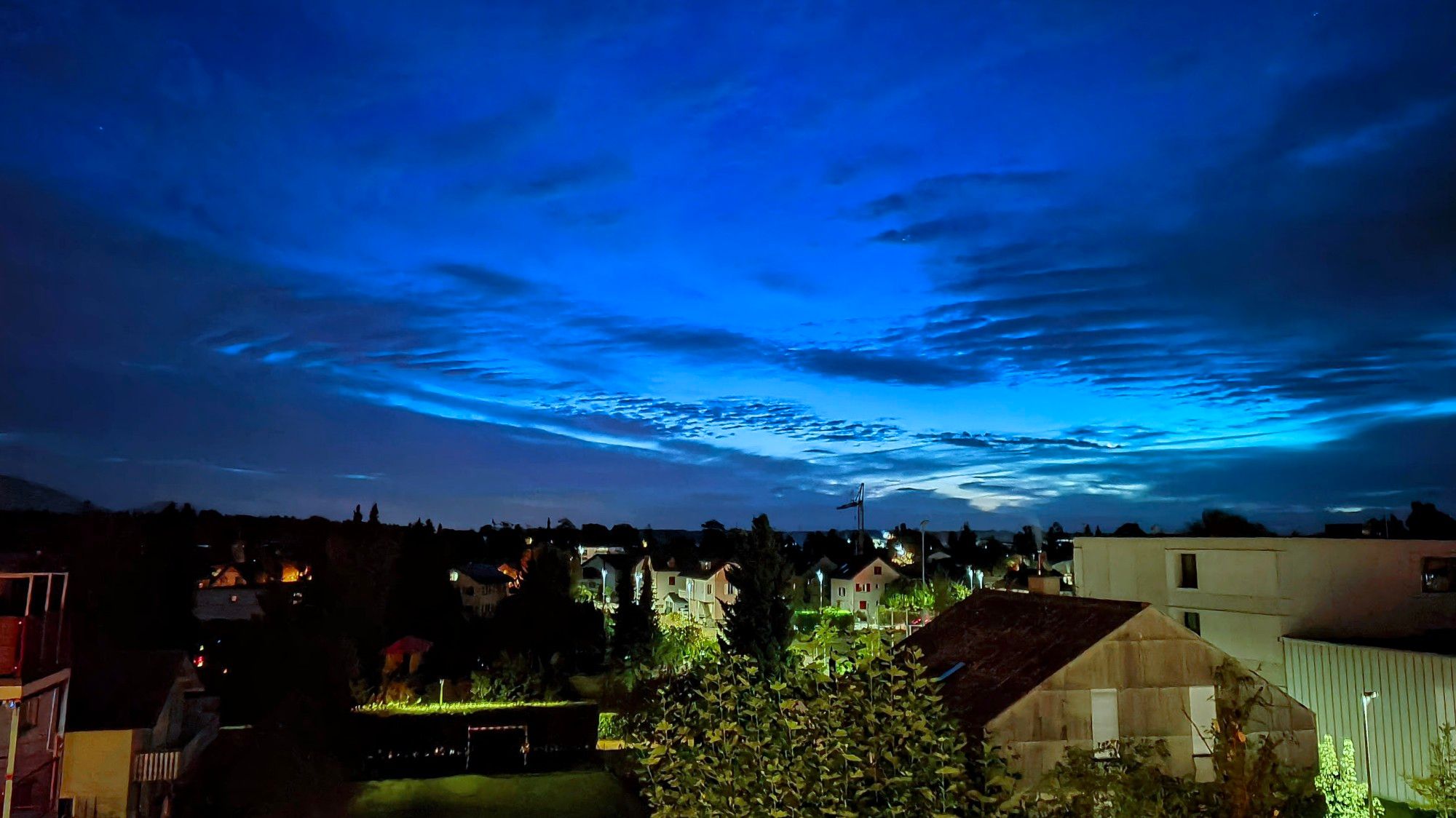 Wolken, rechts das Dorf noch im dunklen, links Strassenbeleuchtung bei der Turnhalle.