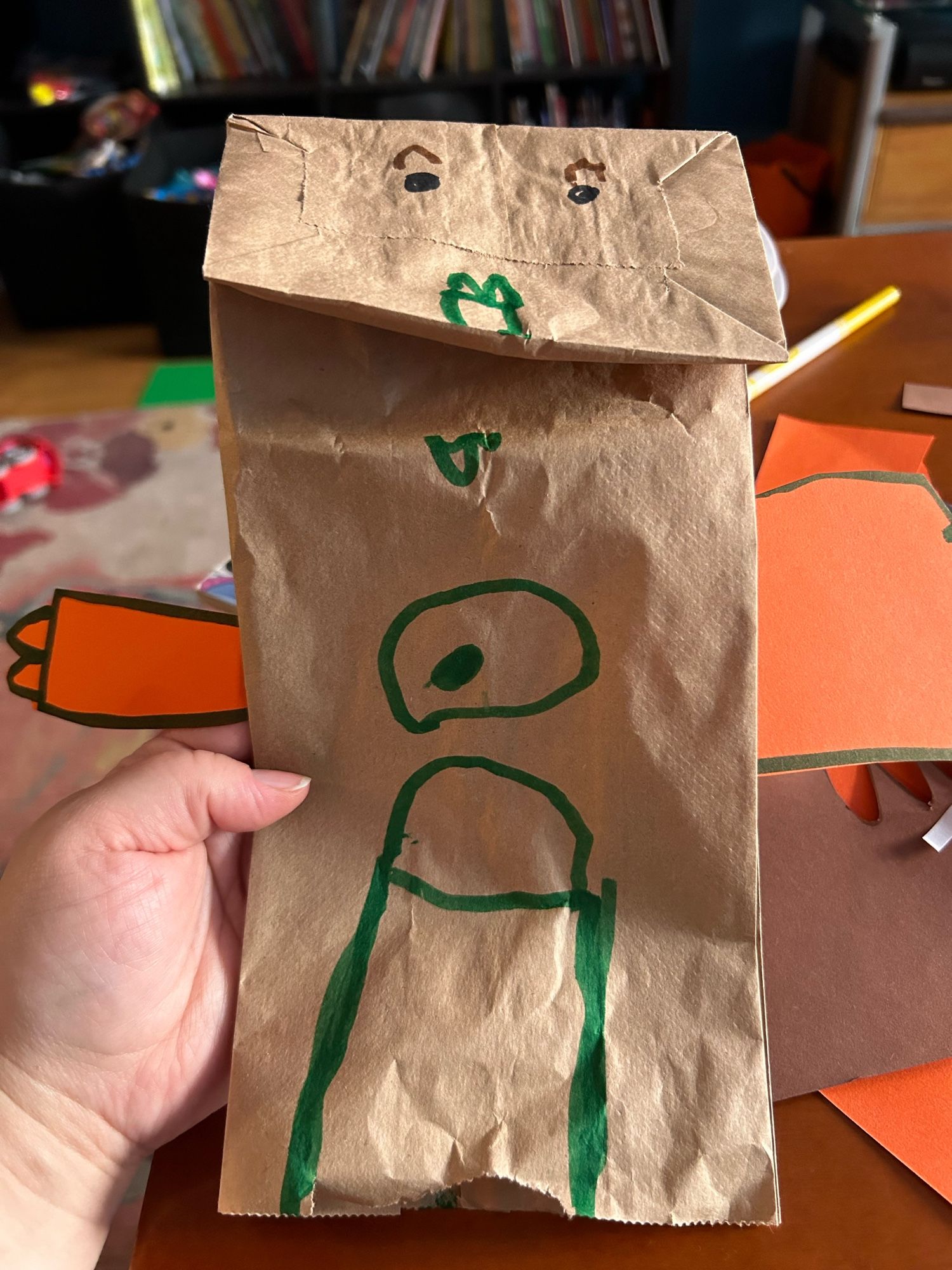 Brown paper bag puppet with orange cut out arms and drawn features. The mouth and eyes are normal but what was intended to be pants looks like a sex organ that rhymes with Venus.