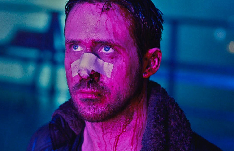 Screenshot from Bladerunner 2049 of Ryan Gosling’s face lit up in pink