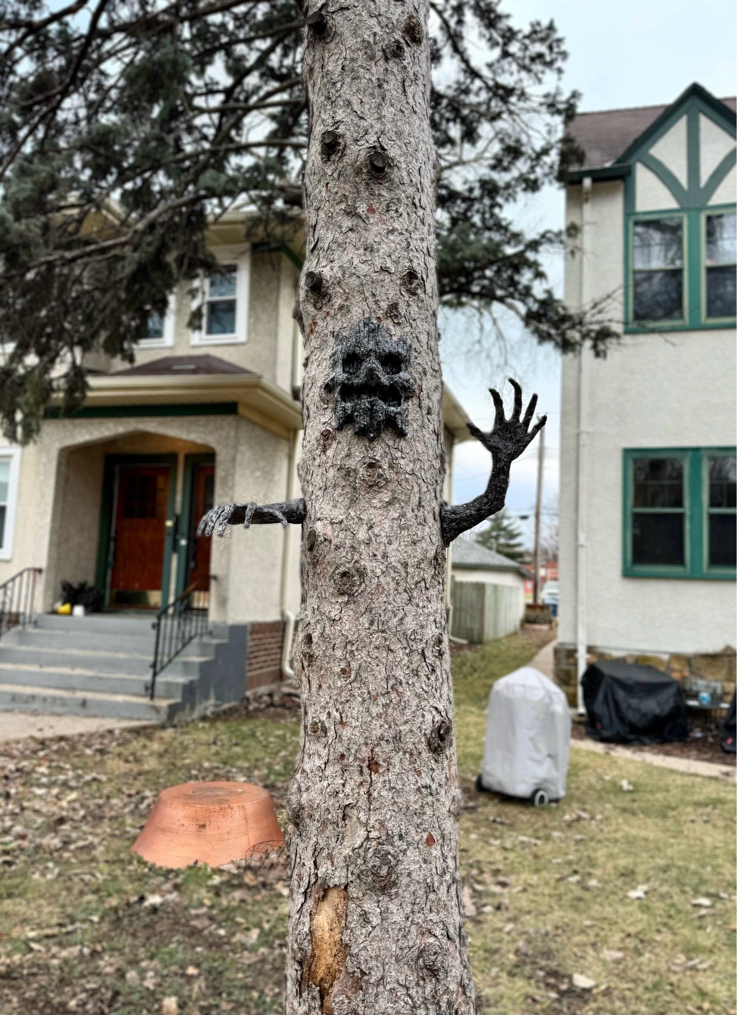 Tree with spooky mask and arms attached to to trunk