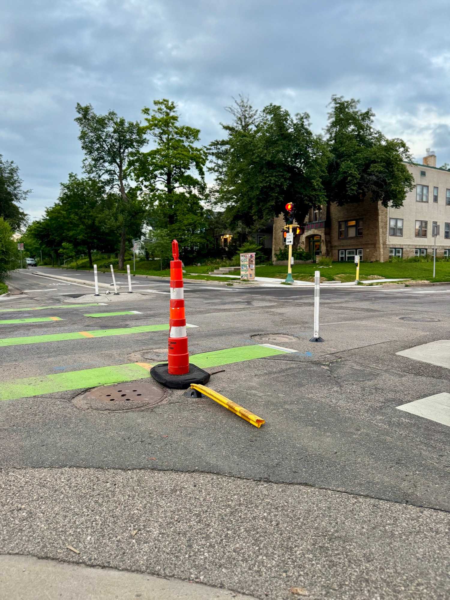 A large cone is in front of a smashed yellow flex post