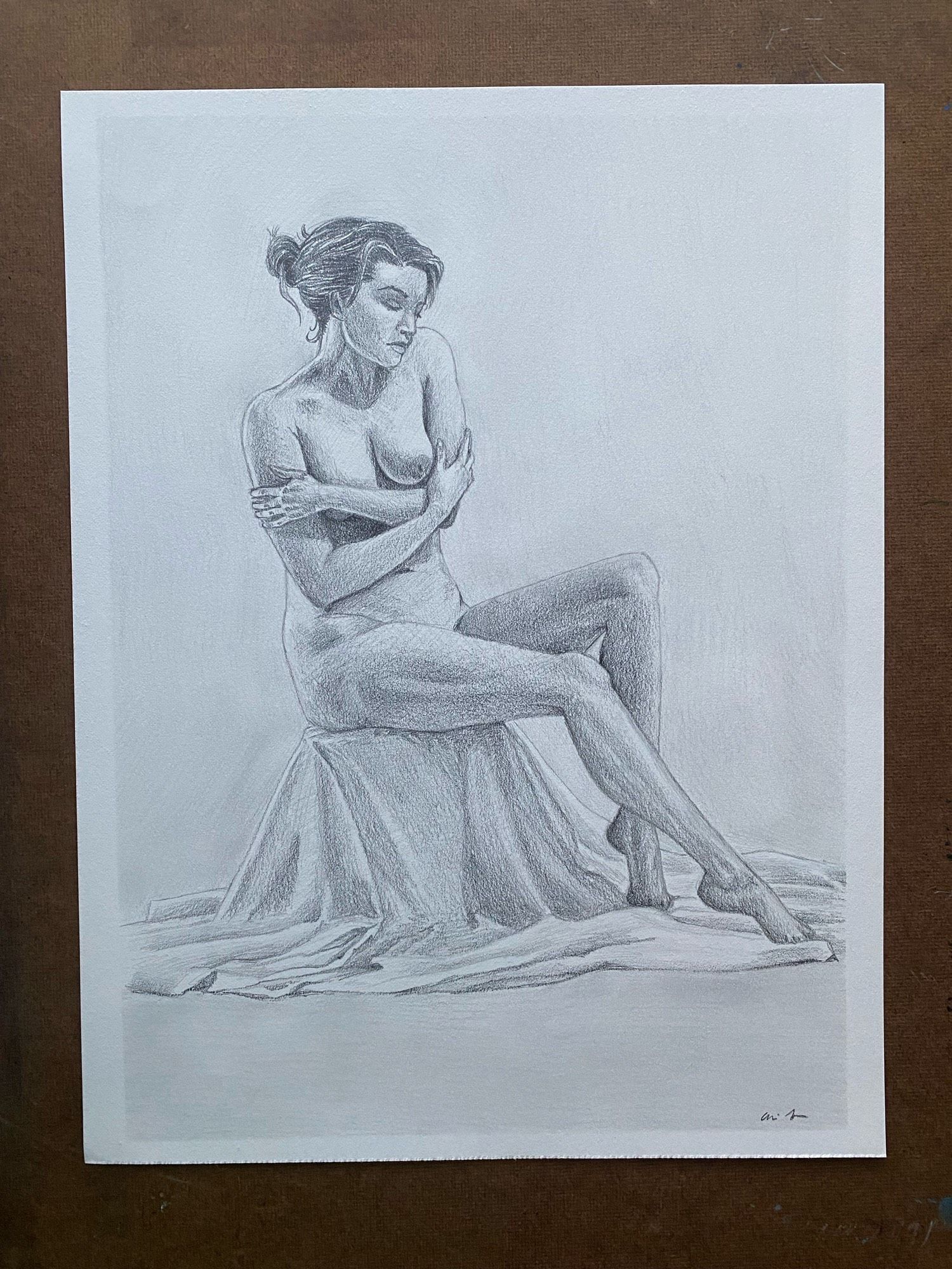 a tonal pencil drawing of a nude woman sitting on a cloth-covered box