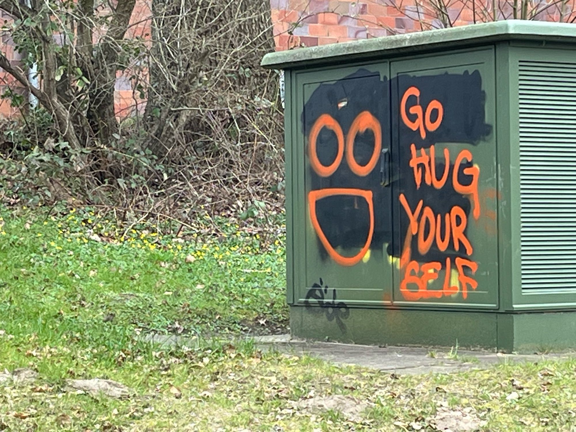 Stromkasten, auf dem eine Hassbotschaft übersprüht wurde mit den Worten: Go hug yourself mit Smiley