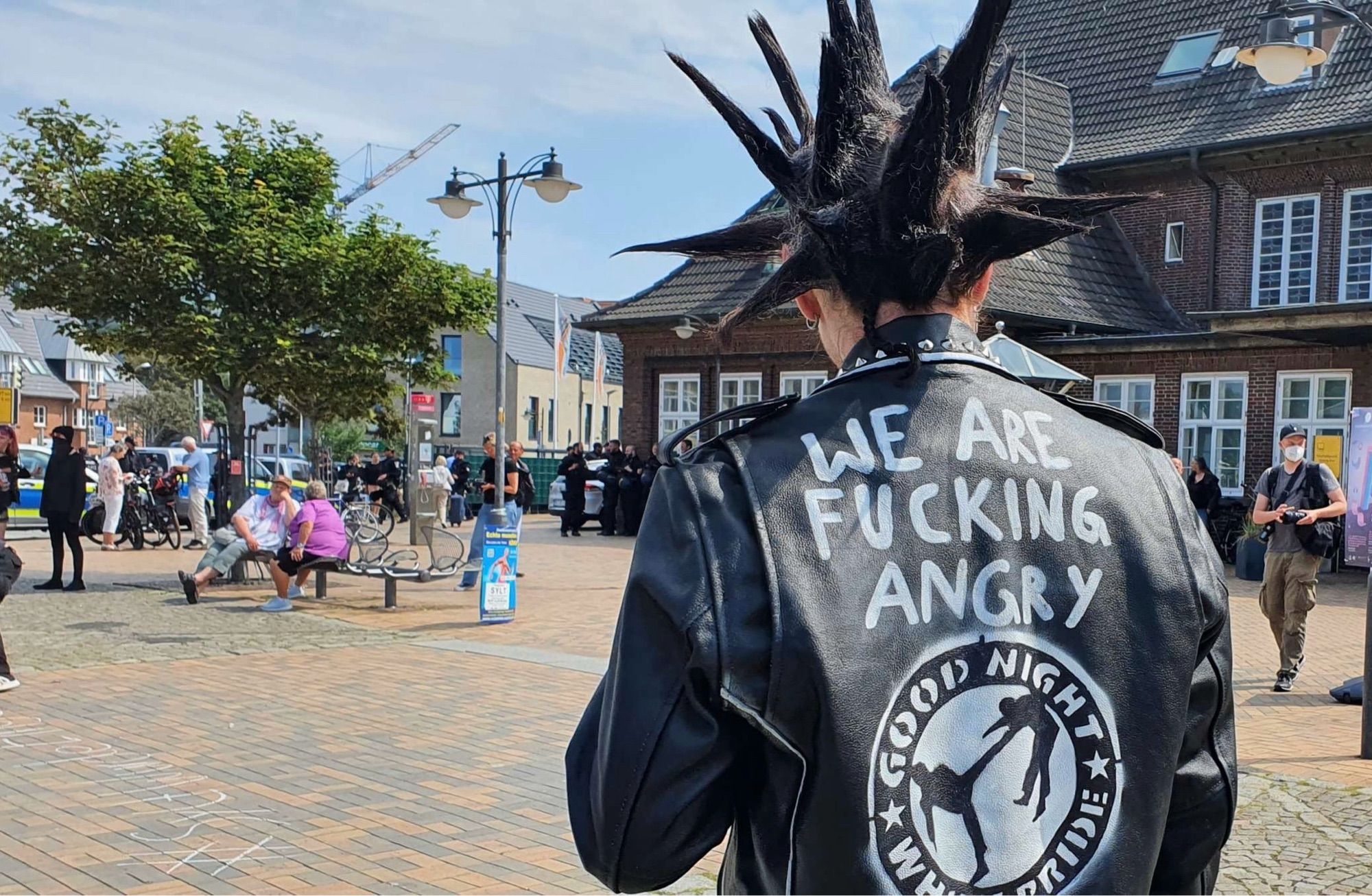 Punk auf Sylt vor dem Westerländer Bahnhof mit Jackenaufschrift :“We are fucking angry“ und Emblem „Good Night white pride“