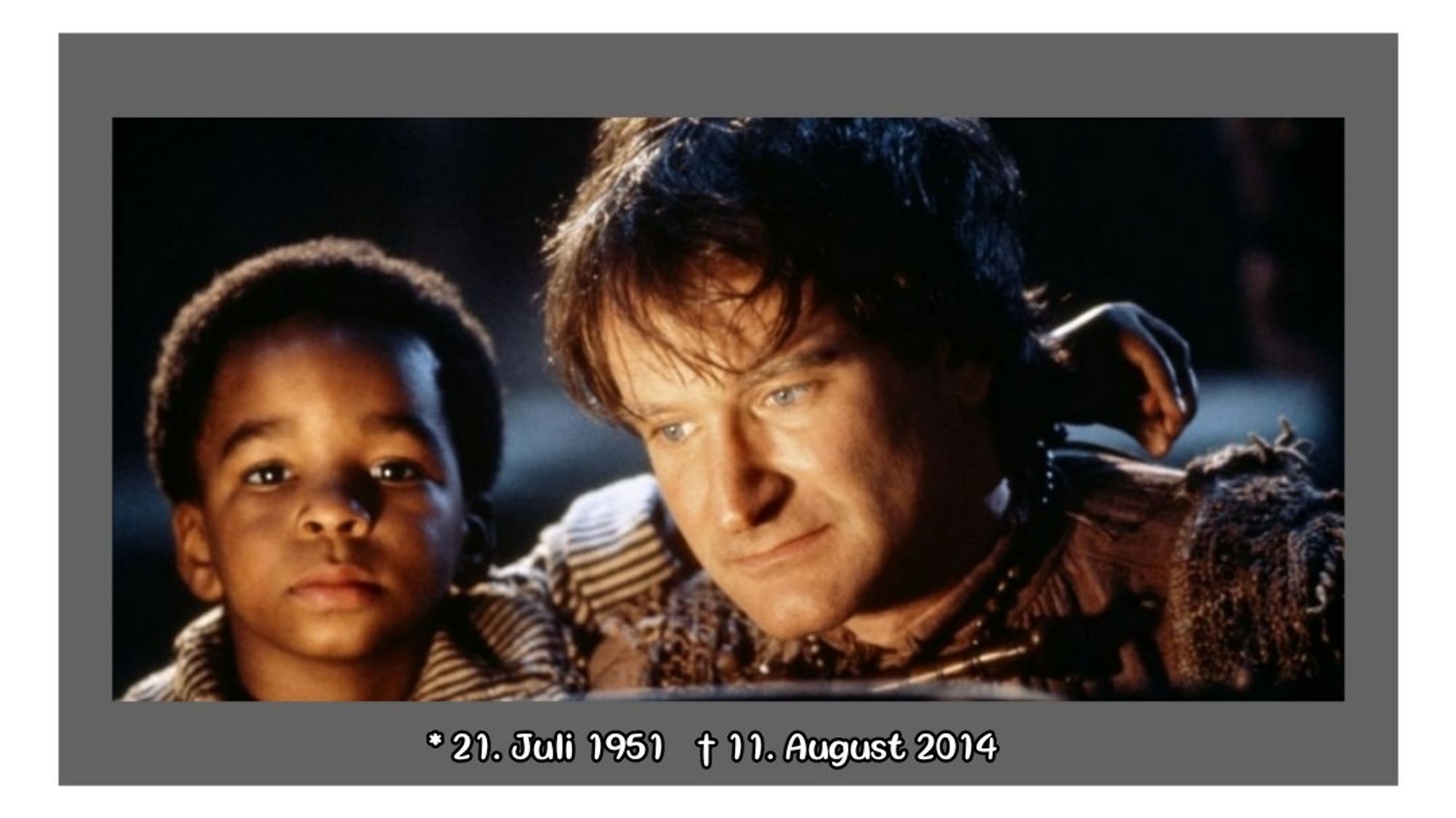 Screenshot von Robin Williams in seiner Rolle als Peter Pan. Er schaut nachdenklich nach unten. Einer der verlorenen Jungs ist neben ihm und legt seinen Arm um ihm.