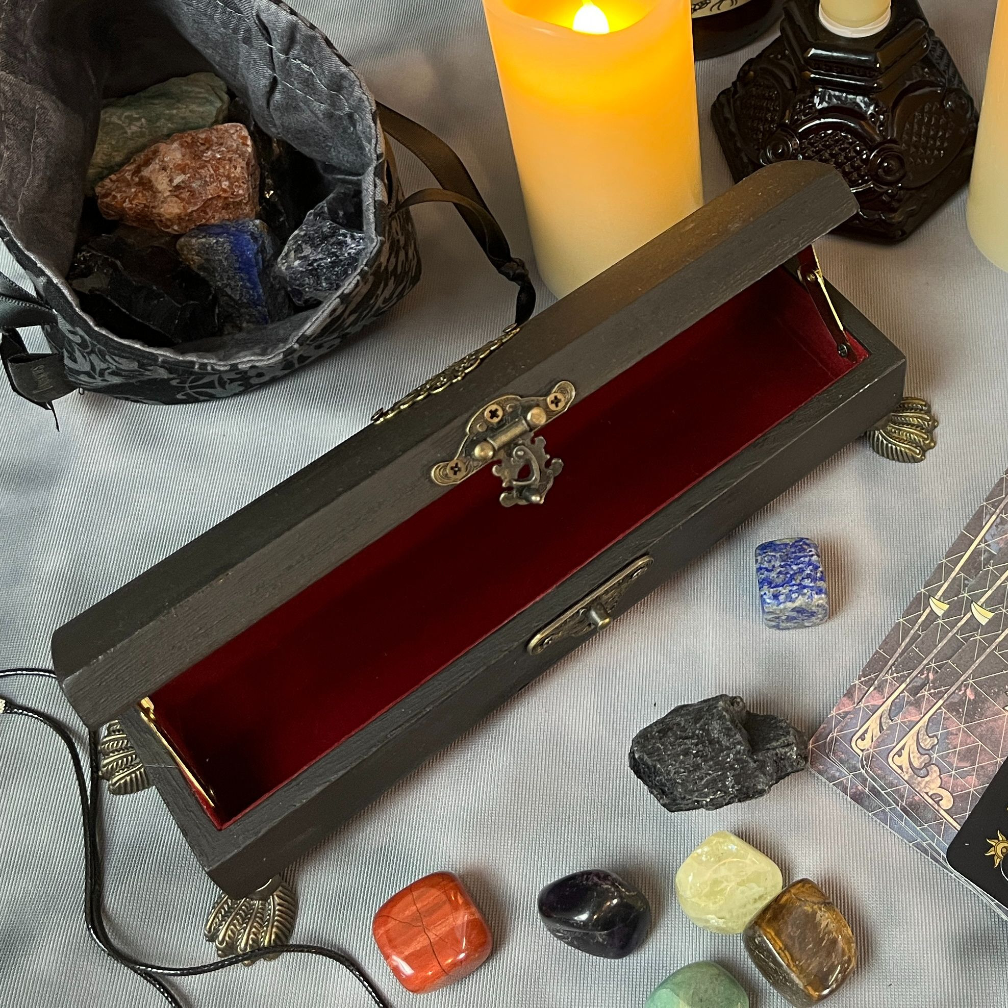 Black coffin dice vault with red felt lining and antique brass hardware.