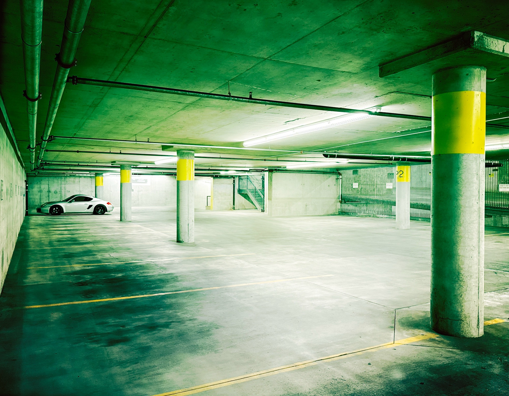 A Porsche Cayman at the far end of an empty underground parking garage. 