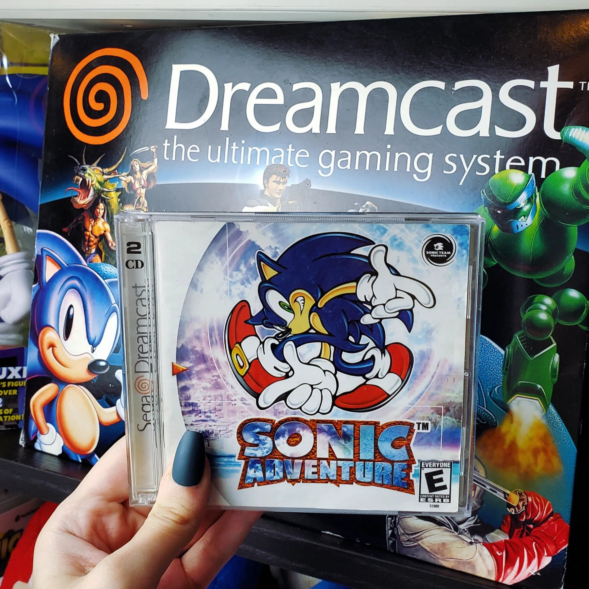 CIB Sonic Adventure game being held in front of a boxed Dreamcast console