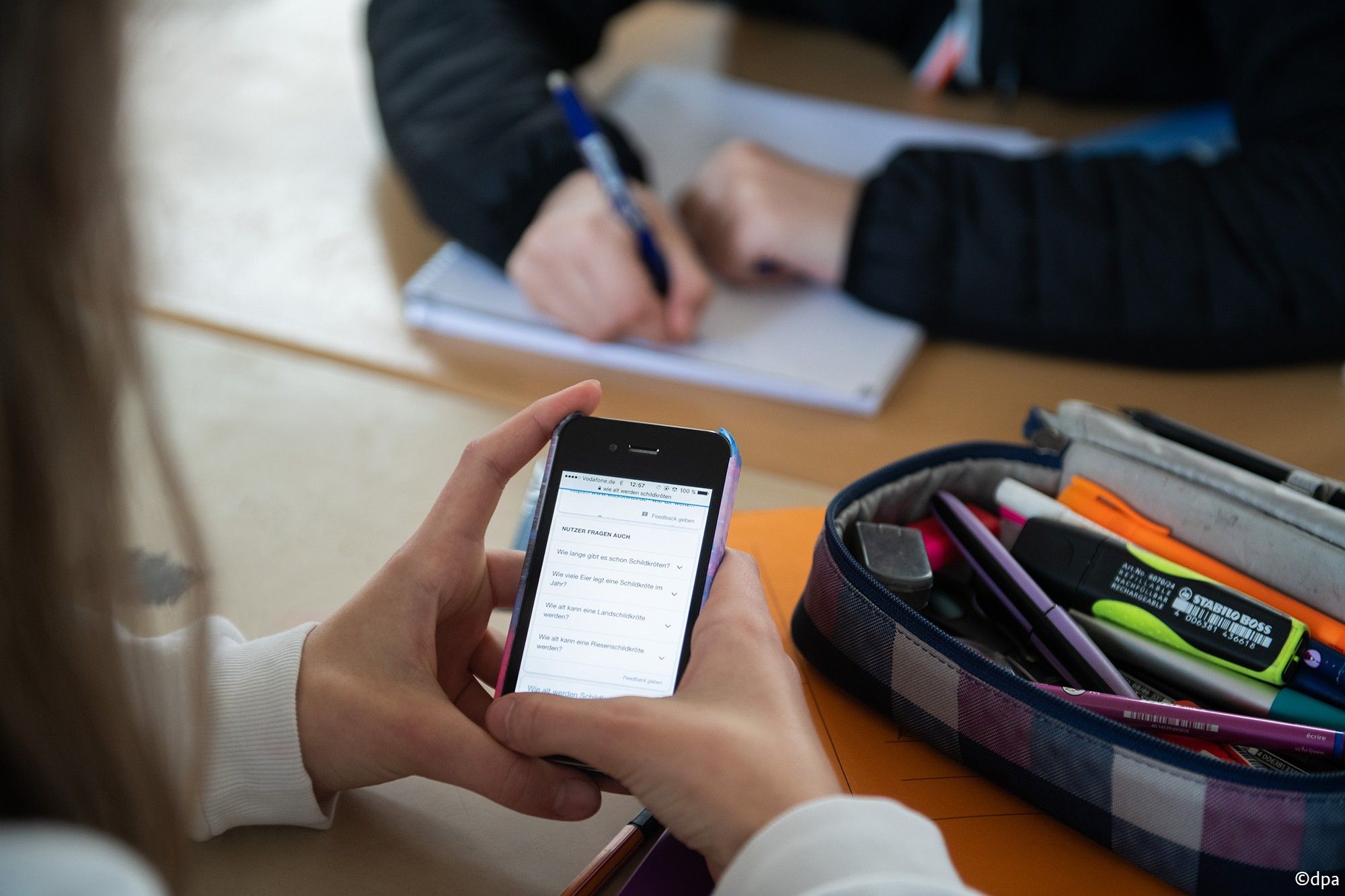 Pupil using a mobile phone in a classroom