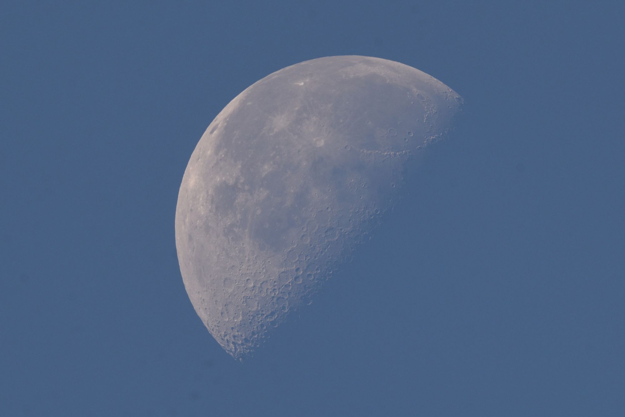 Der abnehmende Mond fast formatfüllend am hellblauen Taghimmel