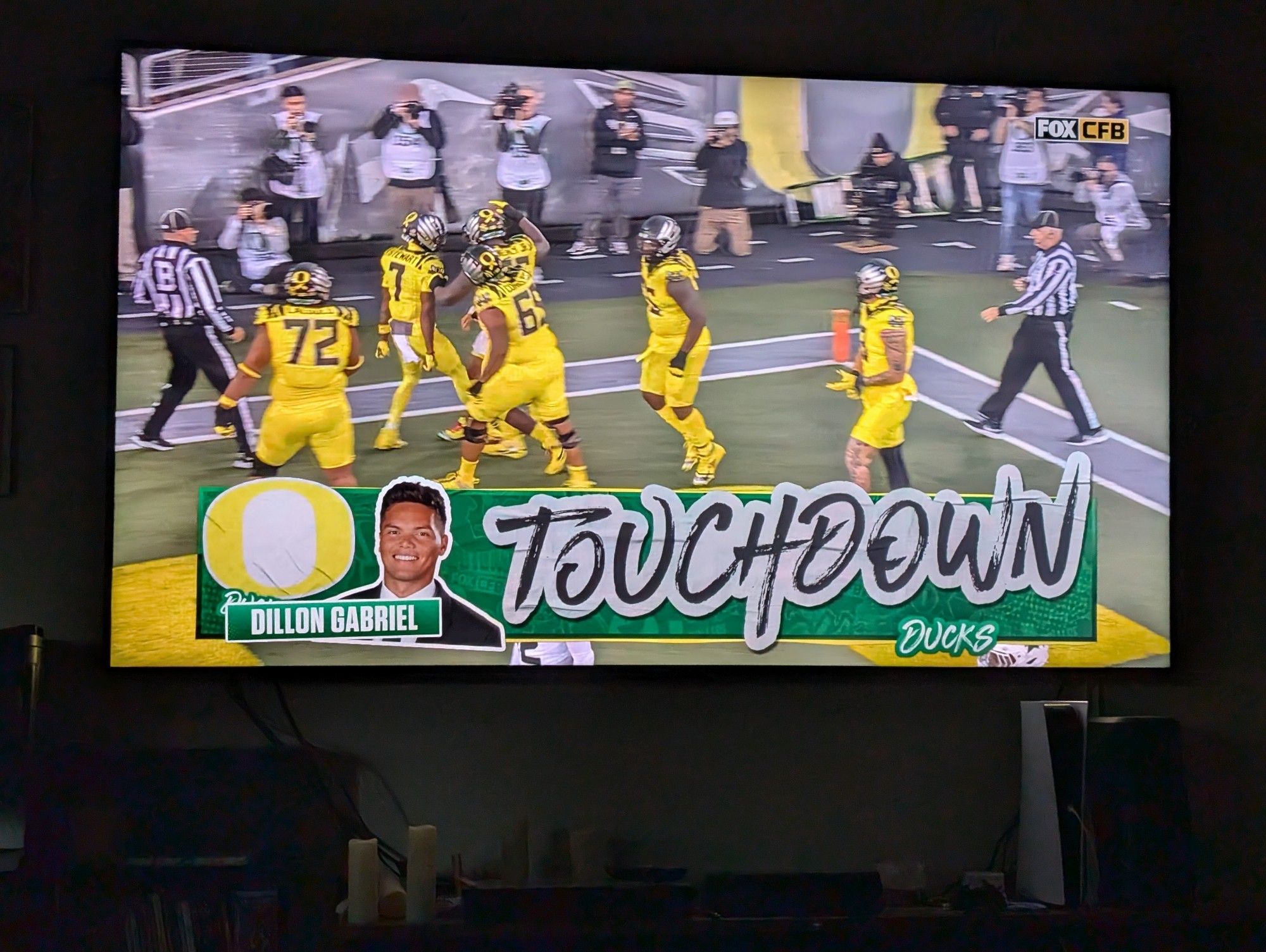 Dillon Gabriel and the Oregon Ducks wearing bright yellow uniforms in the end zone after scoring a touchdown.