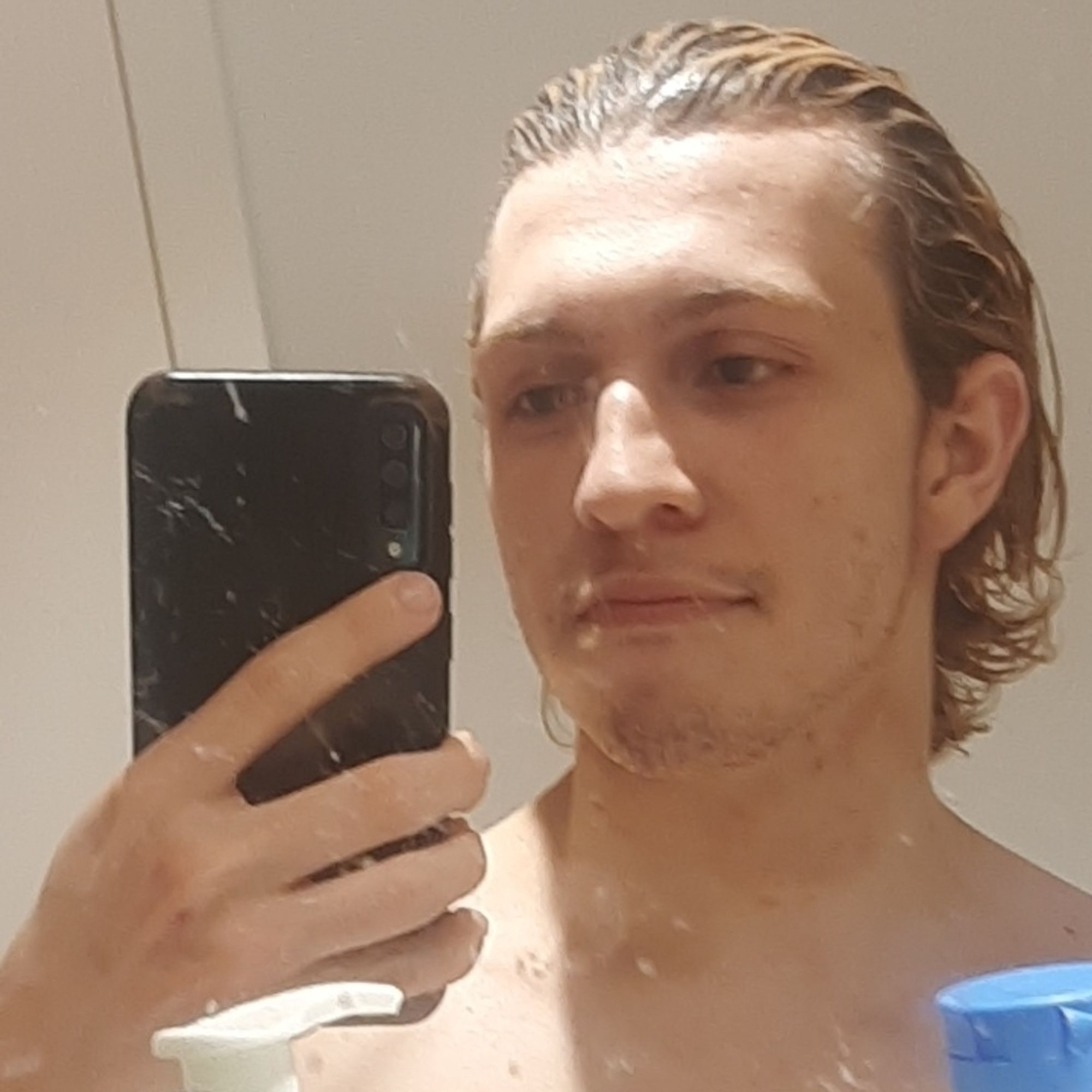 Guy with sleeked back hair taking a mirror selfie