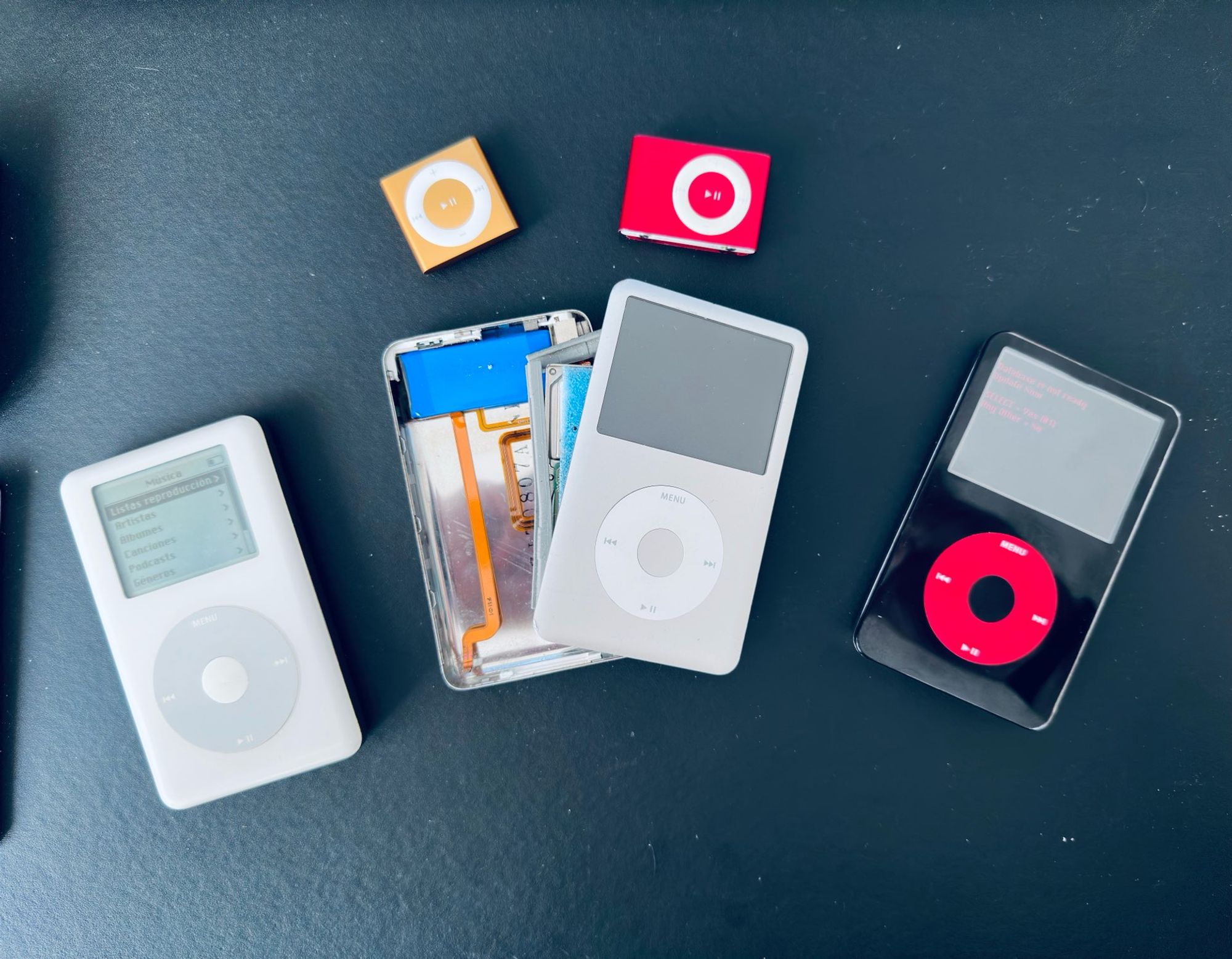 Una mesa llena de iPods antiguos por modificar, reparados o ya modificados.