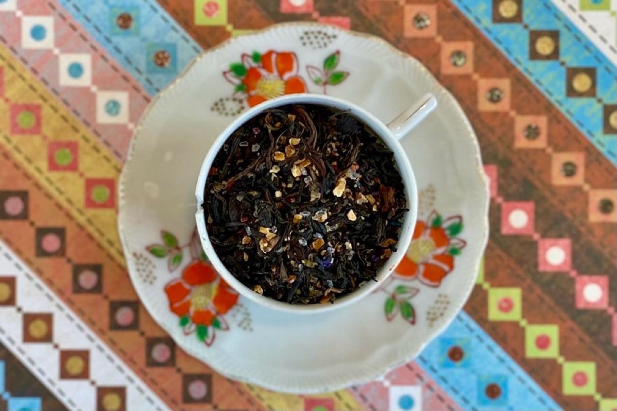 A teacup full of black tea, lime peel, and rainbow sugar sprinkles