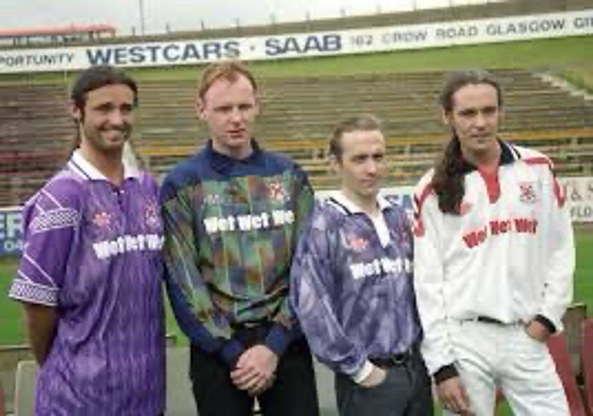 The band members of Wet Wet Wet modelling the 1993 Clydebank away, goalkeeper and home away shirts by Matchwinner, standing in front of the terracing at Kilbowie.