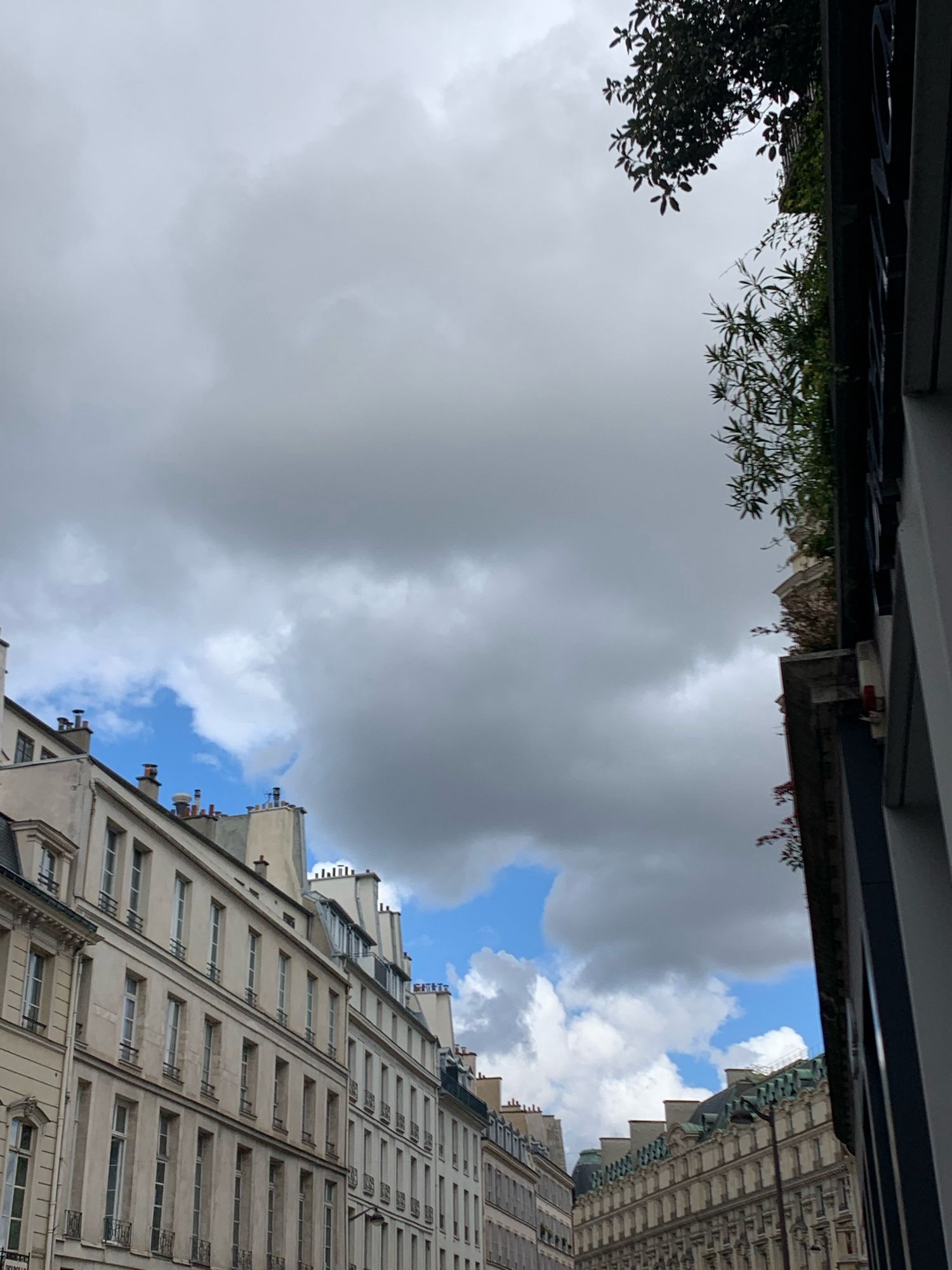 Paris buildings (rue du bac) with bits of blue sky peaking out between white and gray clouds