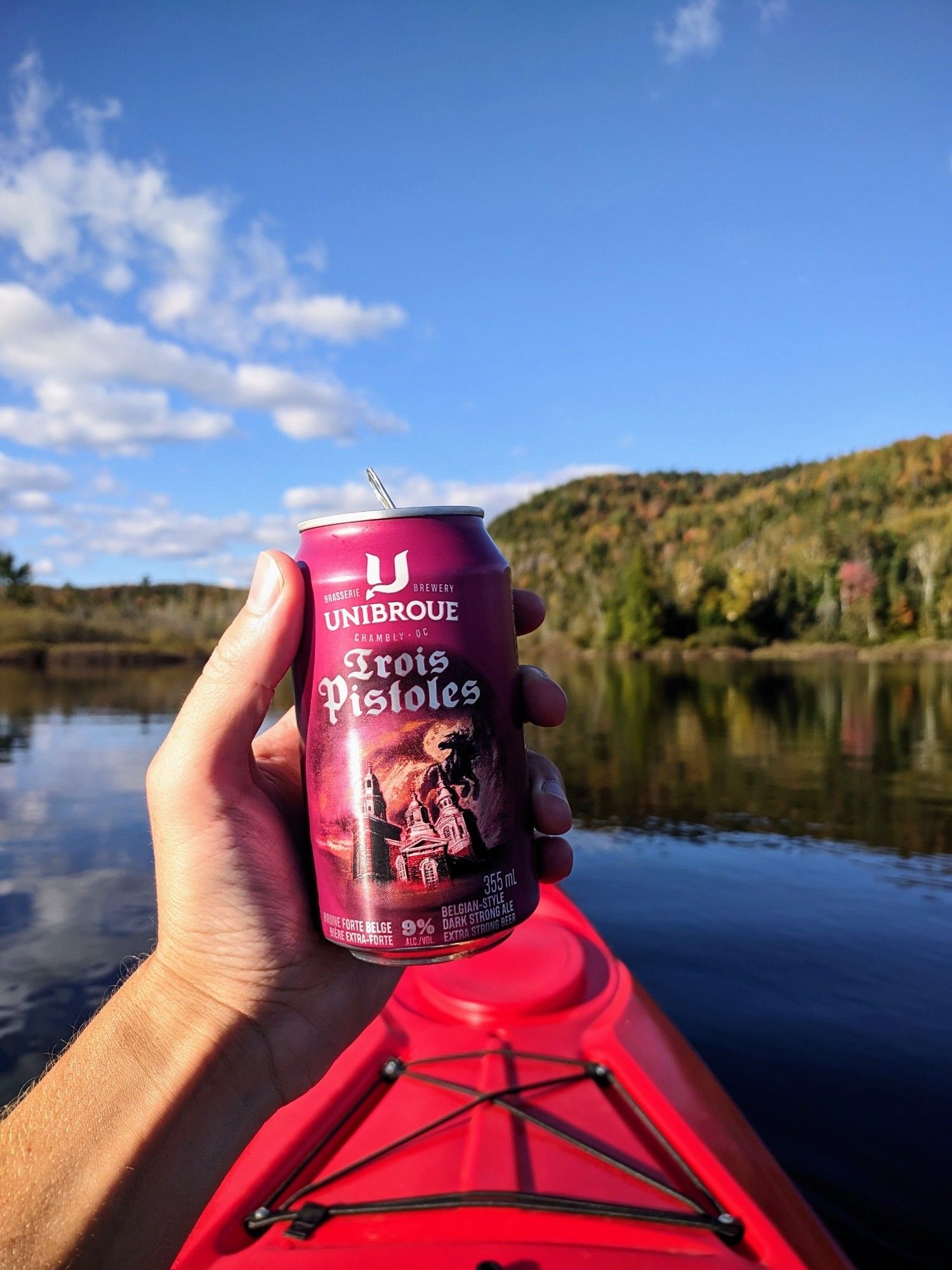 A picture of a can of beer held up to the camera, taken in a kayak.