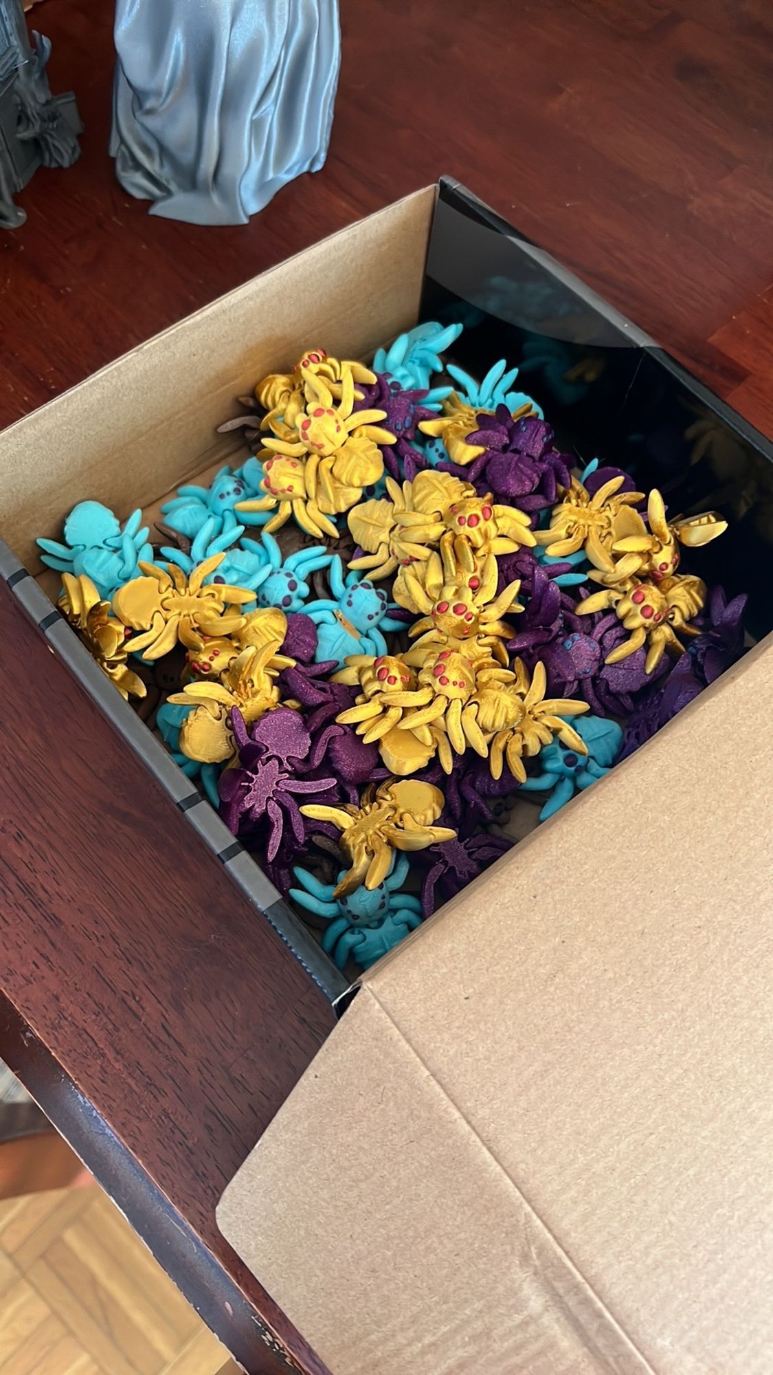 Box full of 3D printed spiders in various colors