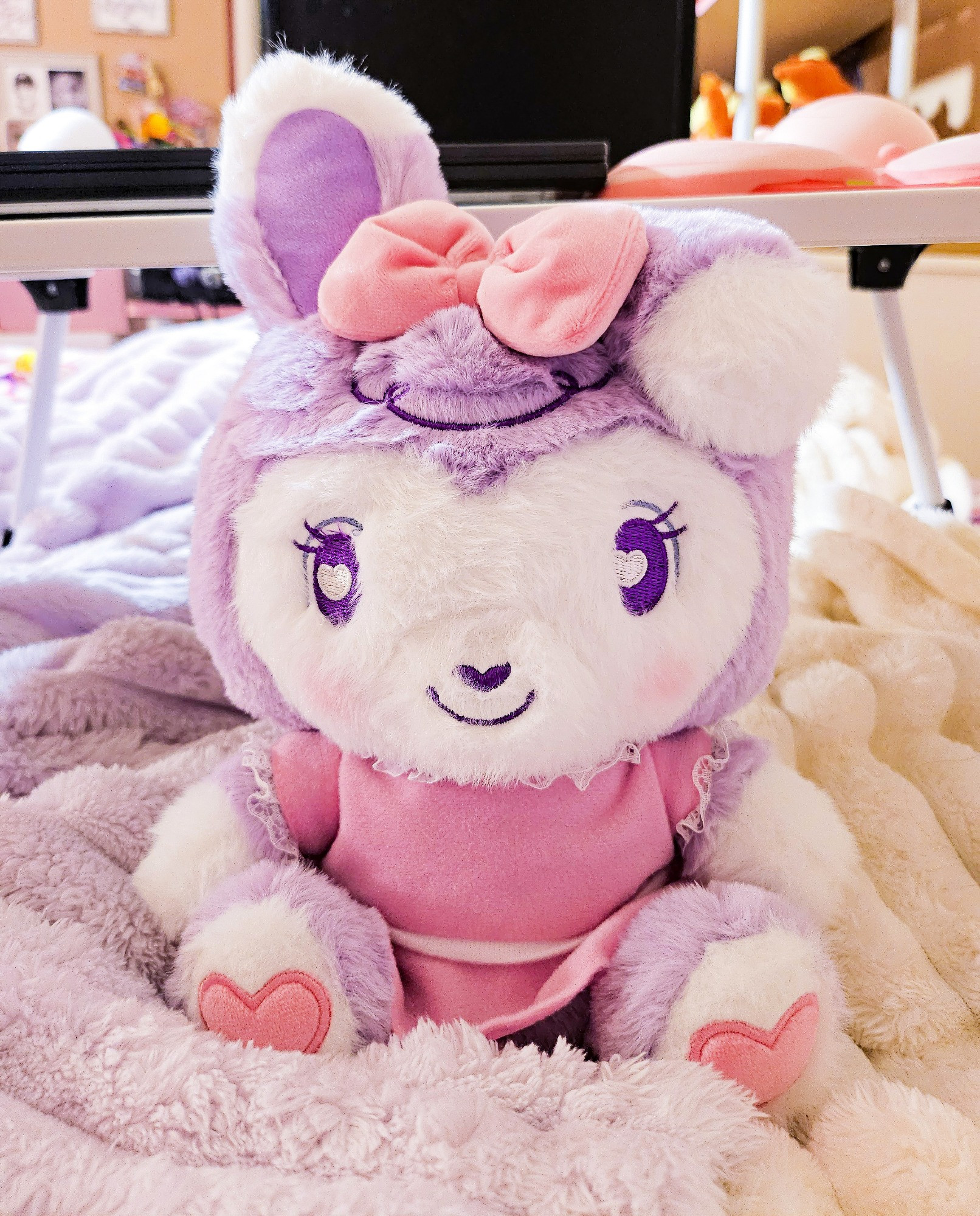 A small purple and white bipedal stylized bunny plushie wearing a pink dress