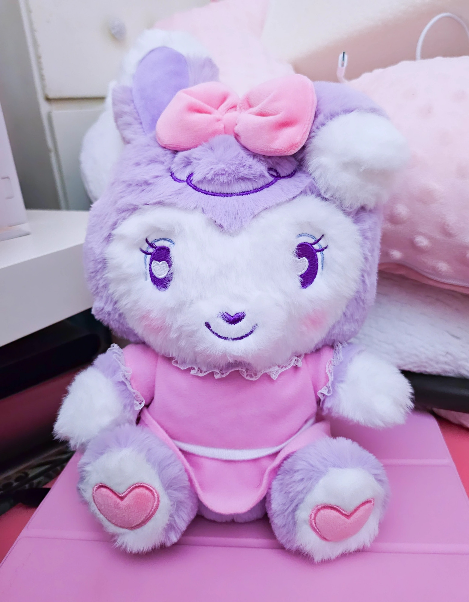 A small purple and white bipedal stylized bunny plushie wearing a pink dress